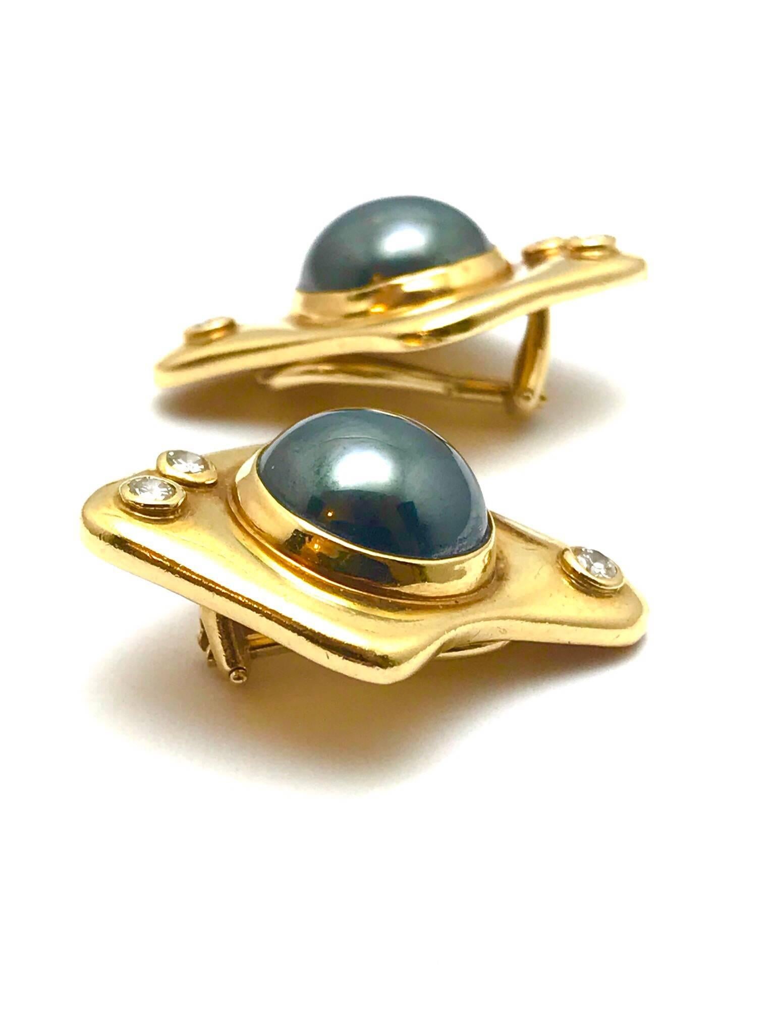 A pair of round diamond and cabochon hematite free form 14 karat yellow gold clip earrings.  the hematite is bezel set in the center, with two diamonds at the bottom of the earrings, and one diamond at the top.  There are six diamonds in total with
