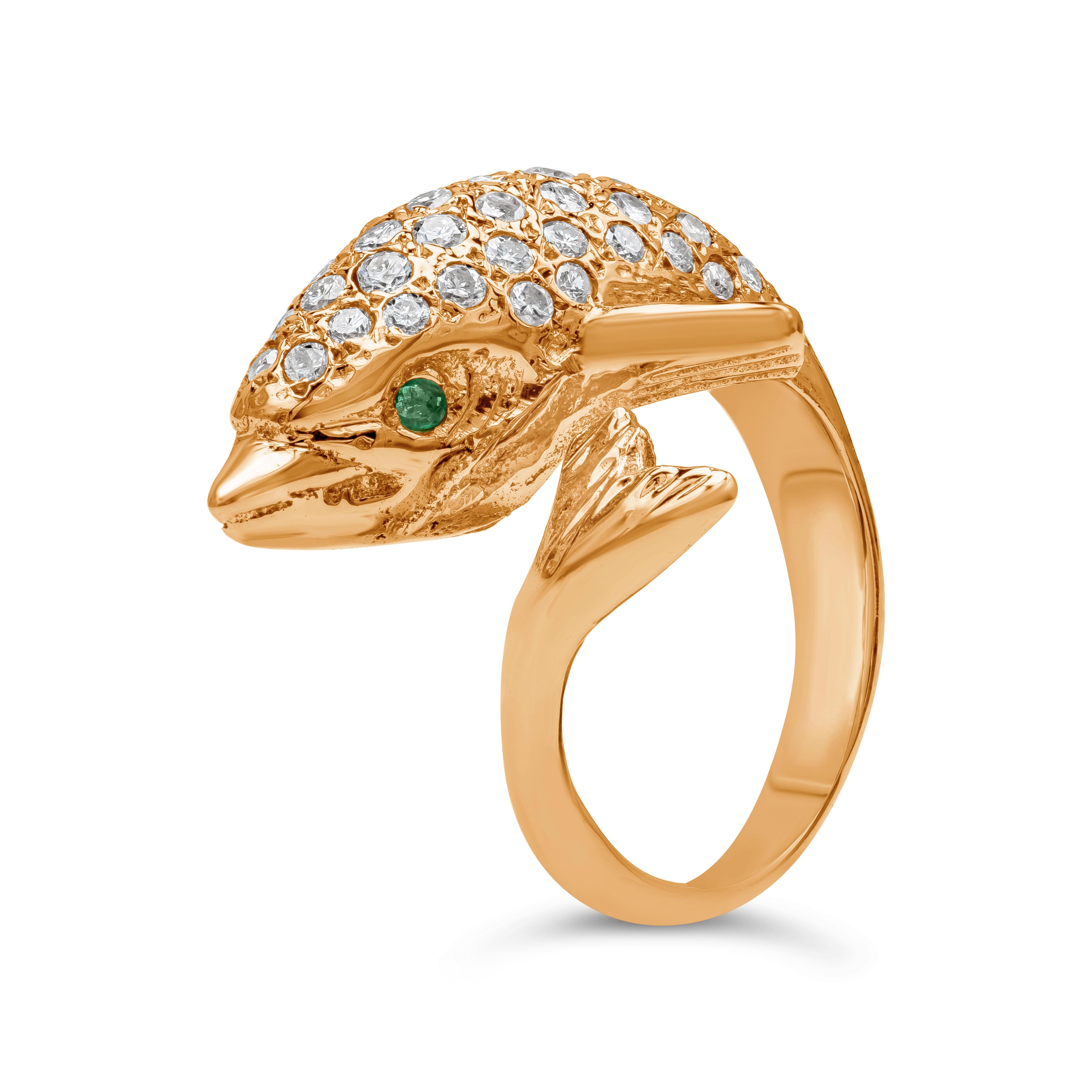 A beautiful and fashionable ring showcasing a dolphin that elegantly wraps around the finger. Set with round brilliant diamonds and green emeralds as the eyes of the dolphin. Made in 14k yellow gold.