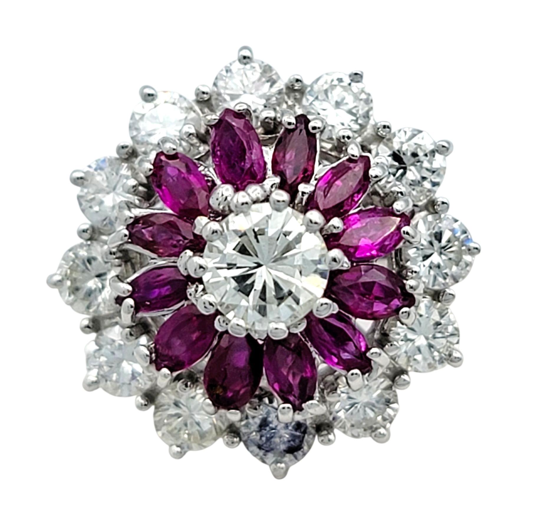 Este llamativo anillo de rubíes y diamantes presenta un atrevido diseño floral que irradia elegancia y vitalidad. El centro está compuesto por vívidos rubíes rojos, dispuestos en un patrón geométrico de pétalos que atrae la mirada con su profundo