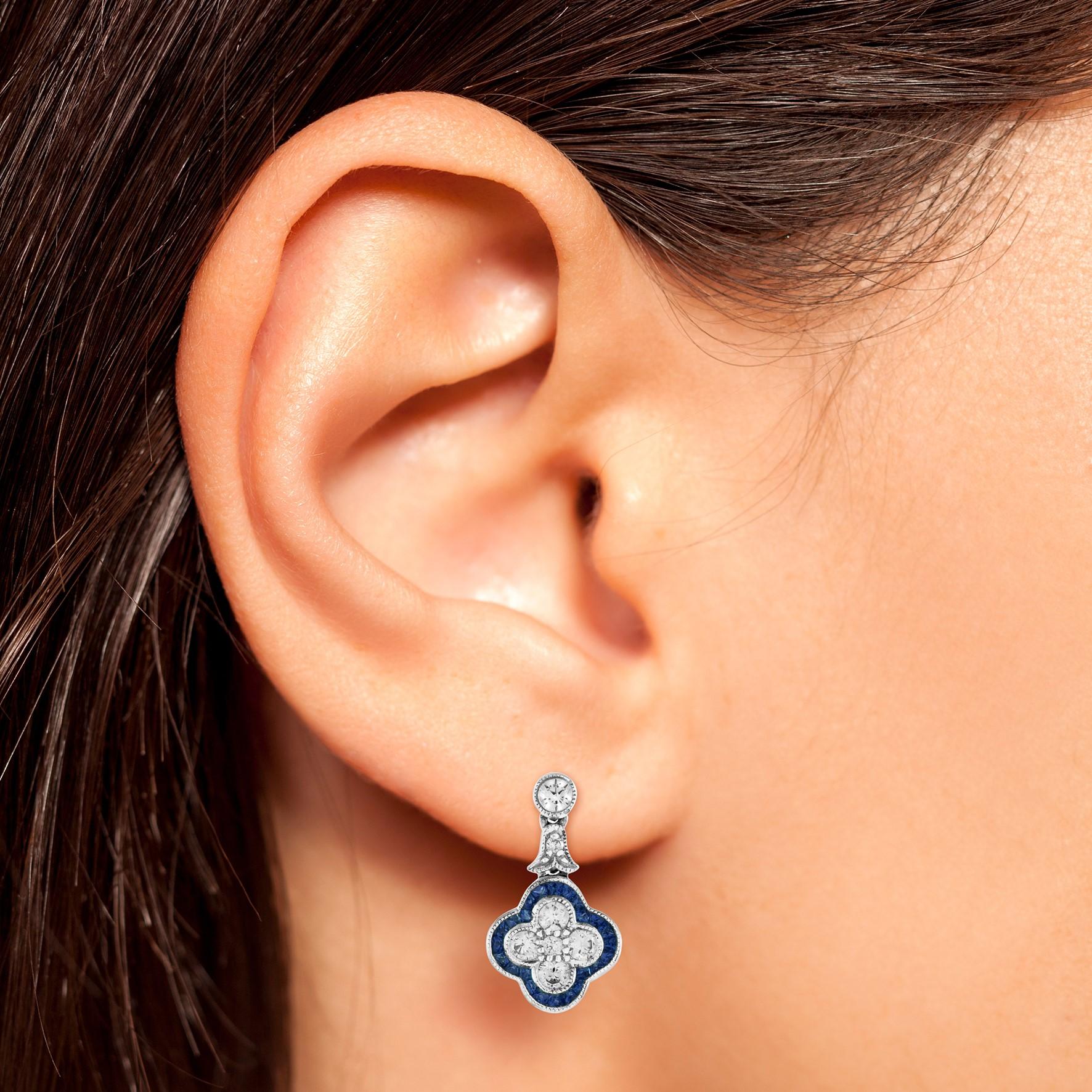 This a lovely pair of earrings for anyone who loves antique-inspired jewelry. Made of dazzling round cut diamond and French cut sapphire set on 18k white gold. A total of fourteen diamonds form a flower with a sapphire trim design for a beautifully