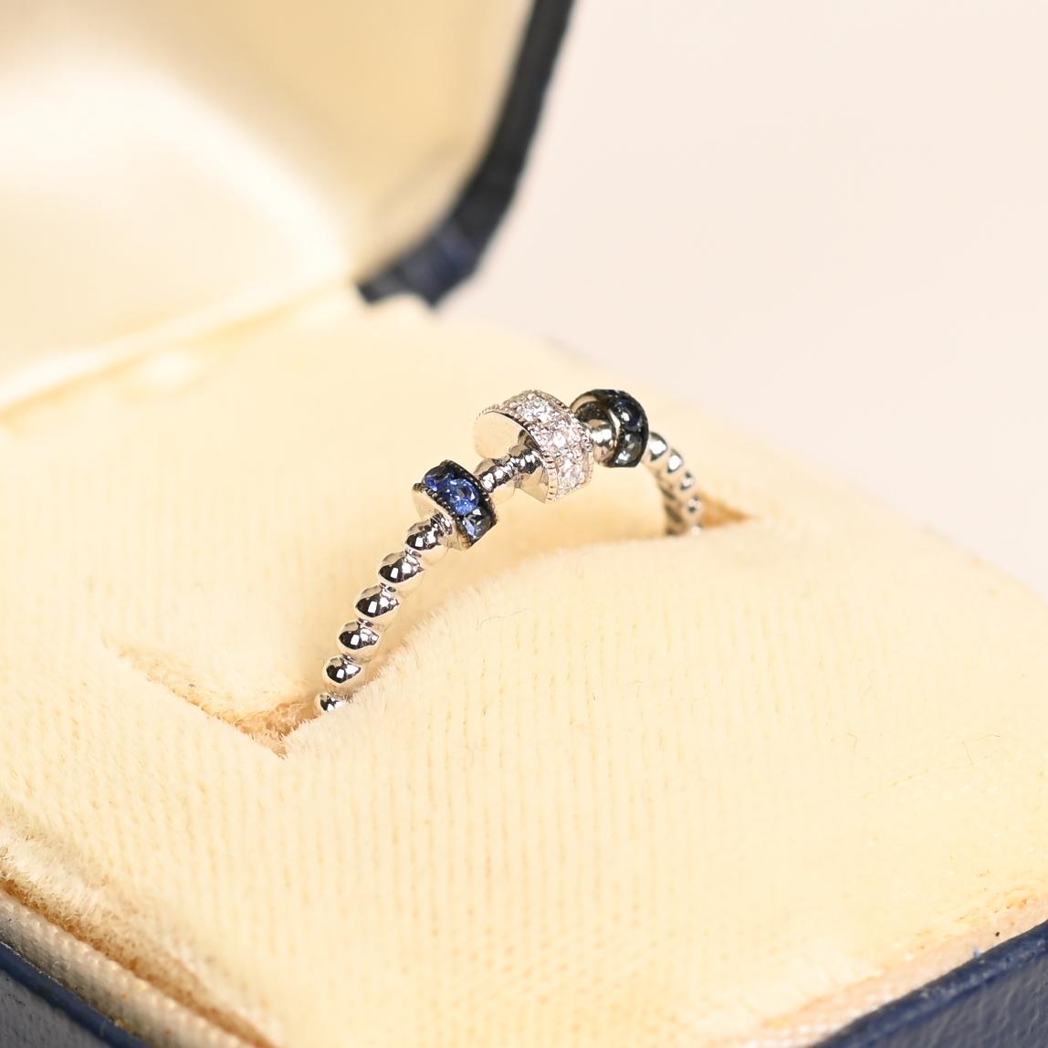 Ce bracelet exquis présente un mélange harmonieux de diamants ronds de taille brillante et de saphirs ronds d'un bleu profond. Les pierres précieuses sont méticuleusement serties en rangs délicats le long des parties gracieusement roulées du