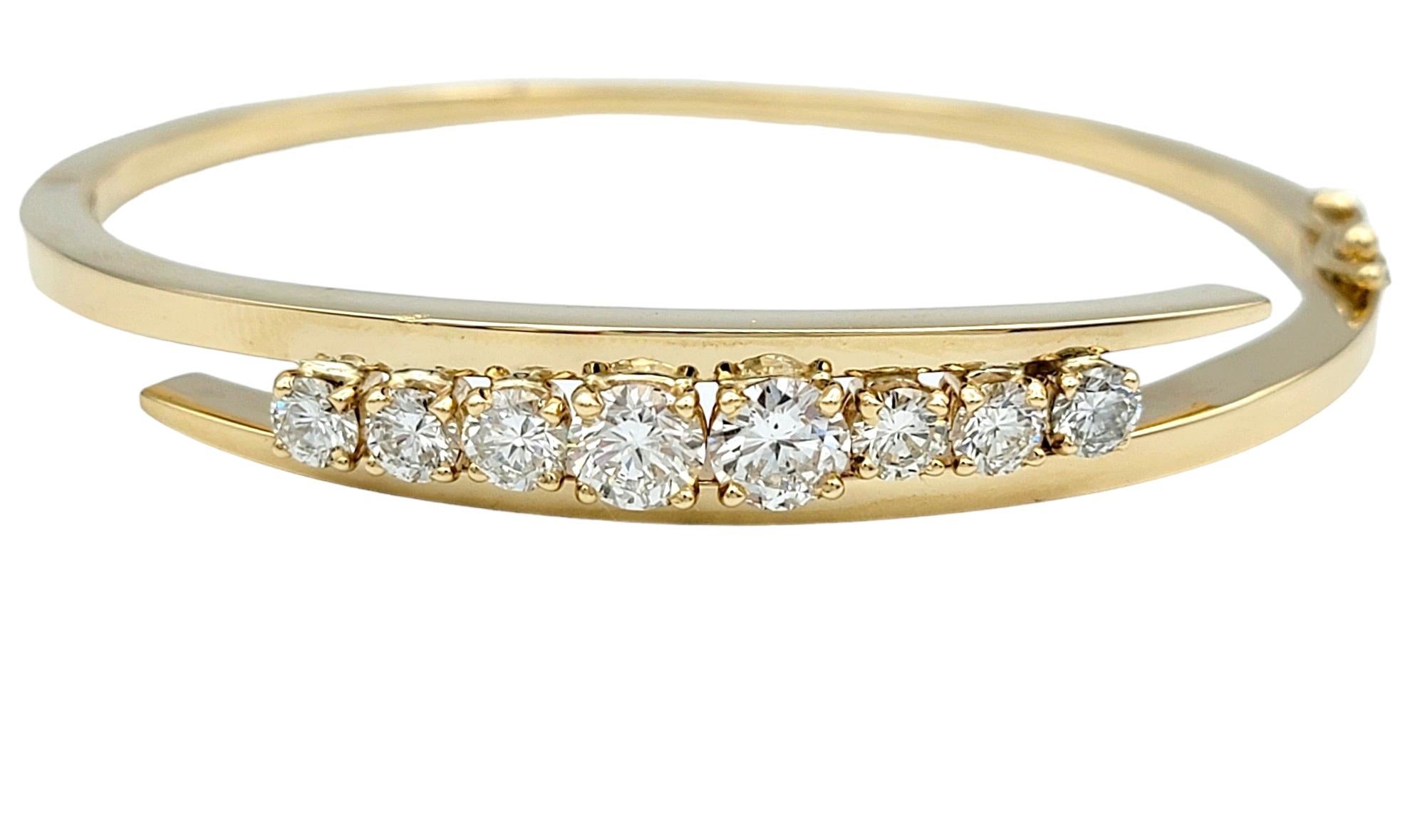 This elegant hinged bangle bracelet exudes sophistication and glamour, crafted in lustrous 14 karat yellow gold. Its timeless design features a bypass style, where the ends of the bracelet gracefully overlap, creating a fluid and dynamic silhouette.