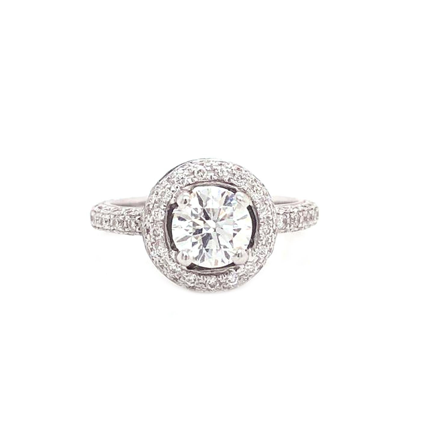 Delicate in design, This extraordinary ring is handcrafted using traditional techniques for exceptional quality. The ring features a GIA certified 1.01 carat round diamond surrounded by a double halo of diamonds on a diamond pave band. This women's