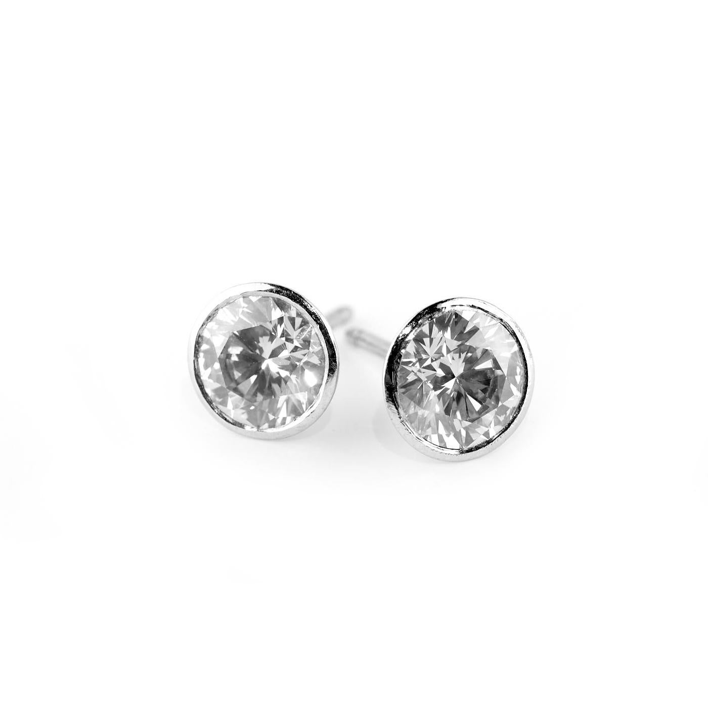Bring traditional style and sparkle to your look with this lovely pair of stud earrings. Each stud features a round-cut, 1.24 / 1.26-carat white diamond in a simple Platinum prong setting. The lovely earrings fasten with screw-back clasps for secure