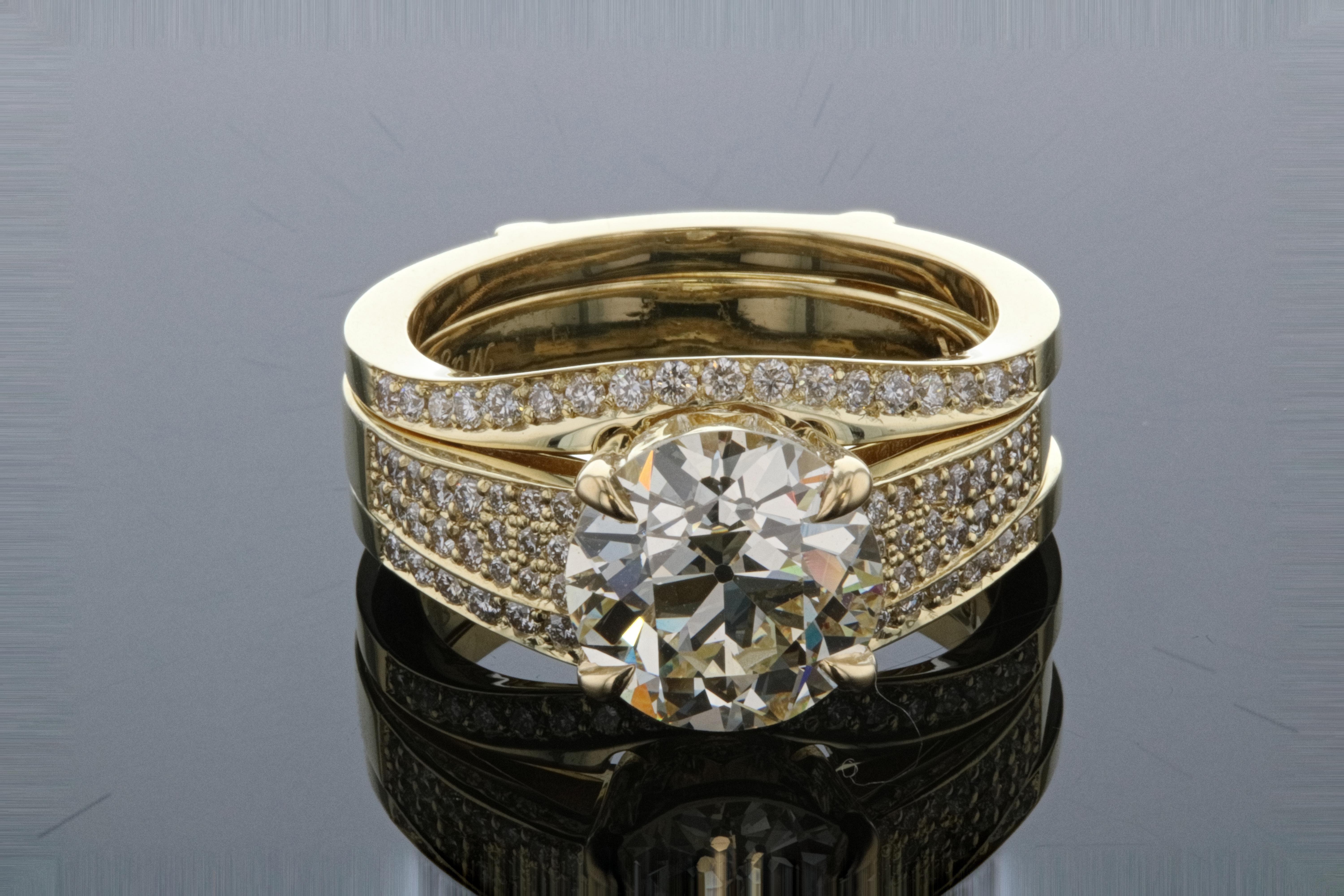 This round diamond engagement ring with matching ring jacket is a perfect pairing! Set with micro pave and a round diamond center stone, hidden details are under the basket. The diamond ring jacket is a perfect match and is crafted in 14k yellow