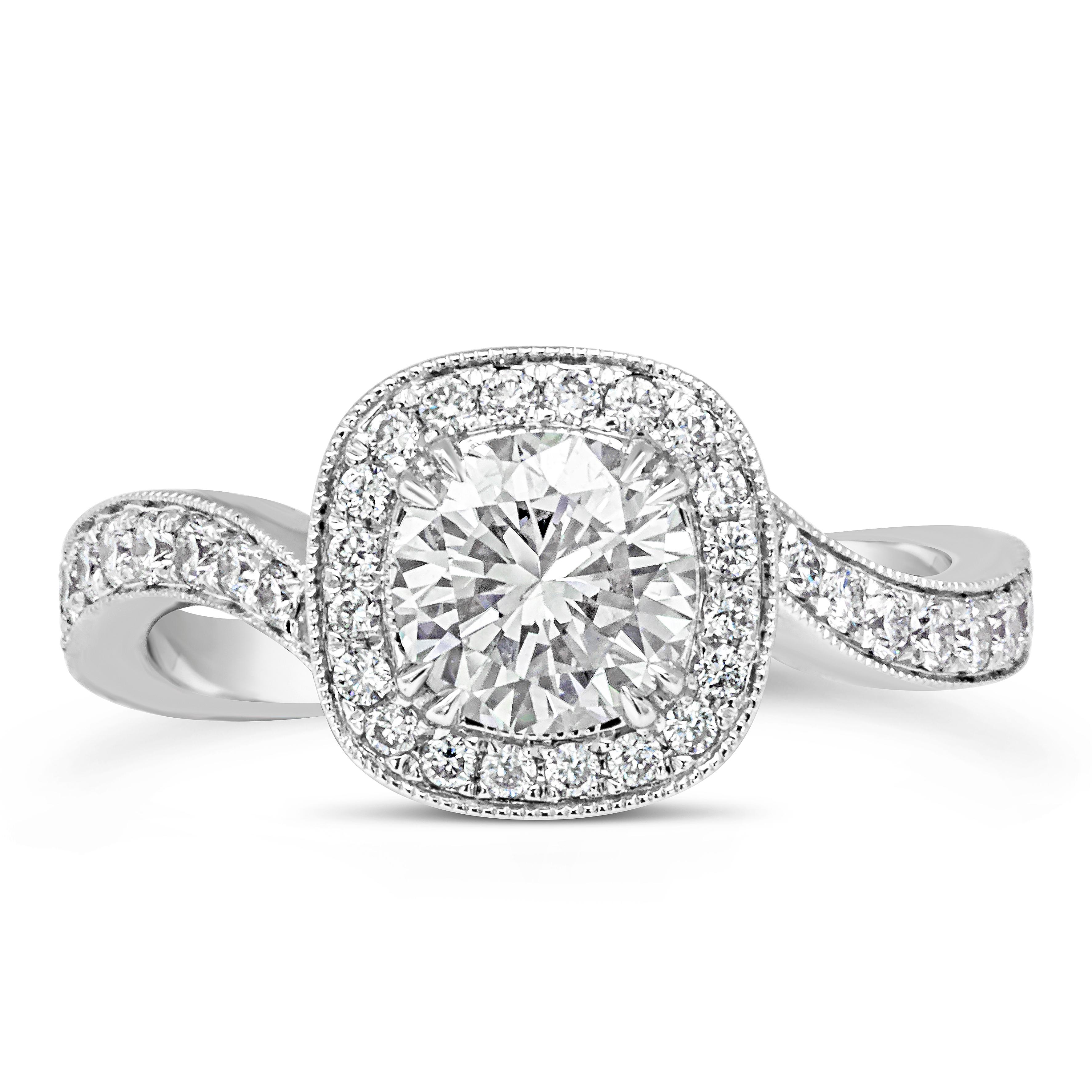 An unusual and intricately designed engagement ring and wedding band set. The engagement ring features a 0.98 carat round brilliant diamond center set in a diamond encrusted cushion halo finished with milgrain edges. The halo is attached to a wavy