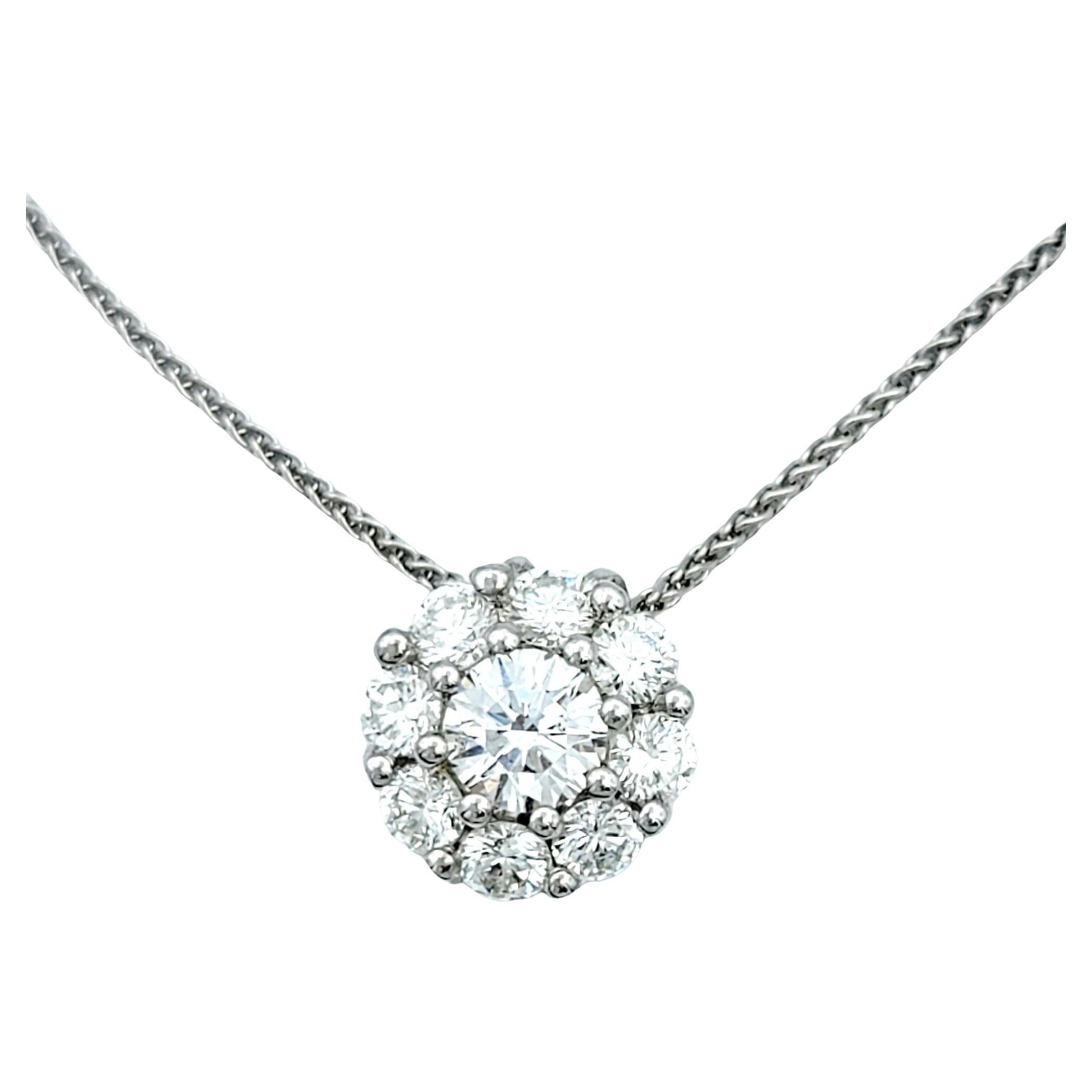 This diamond necklace with its exquisite yet simple design is an absolute marvel. The pendant has a round center diamond, surrounded by smaller halo of round diamonds, creating a beautiful miniature flower-like shape. 

The piece is set in polished