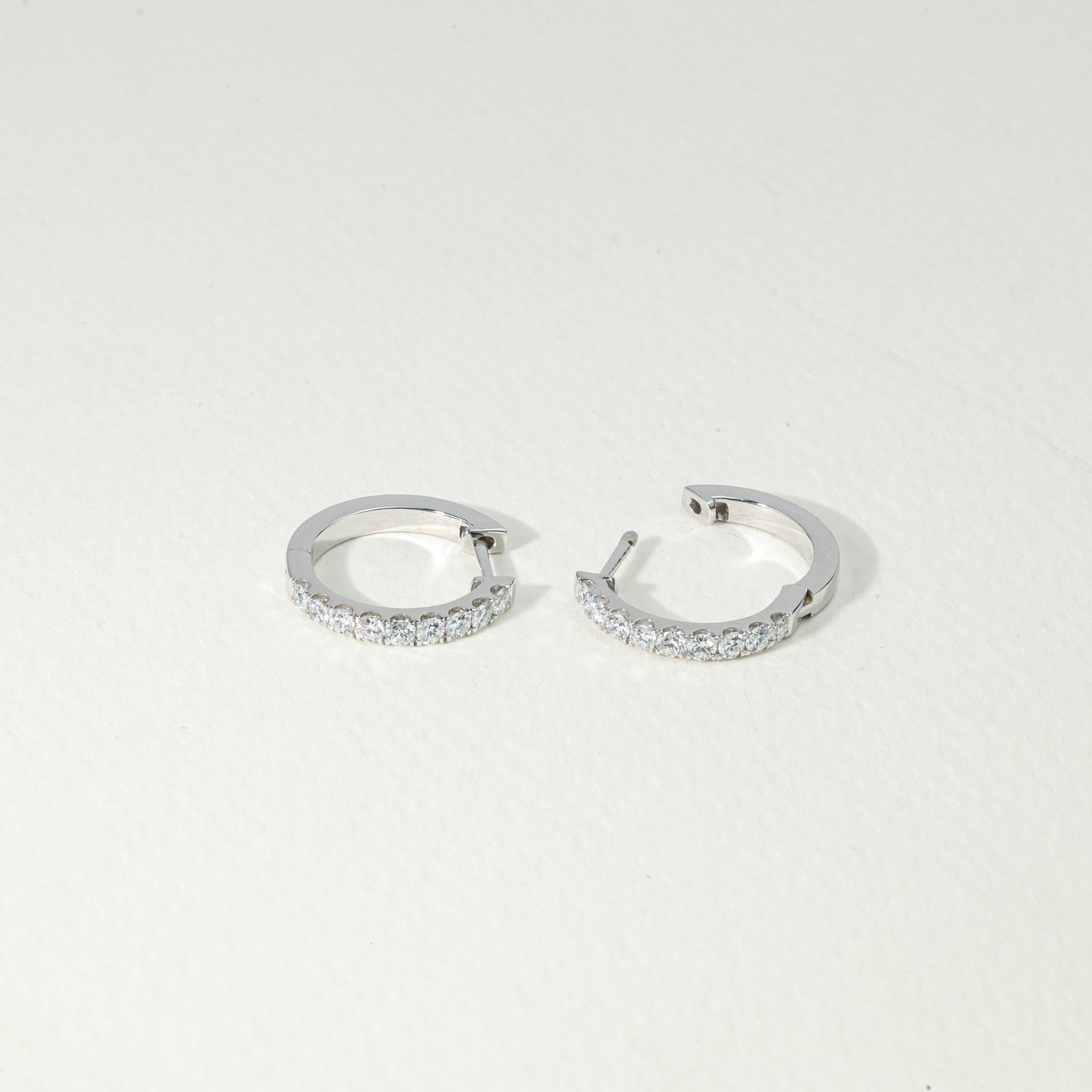 A modern icon of refined sophistication, these diamond huggie hoop earrings are a radiant tribute to understated luxury. Crafted in solid 18K white gold, each hoop gleams with meticulously set natural round-cut diamonds, totaling 0.62 carats of