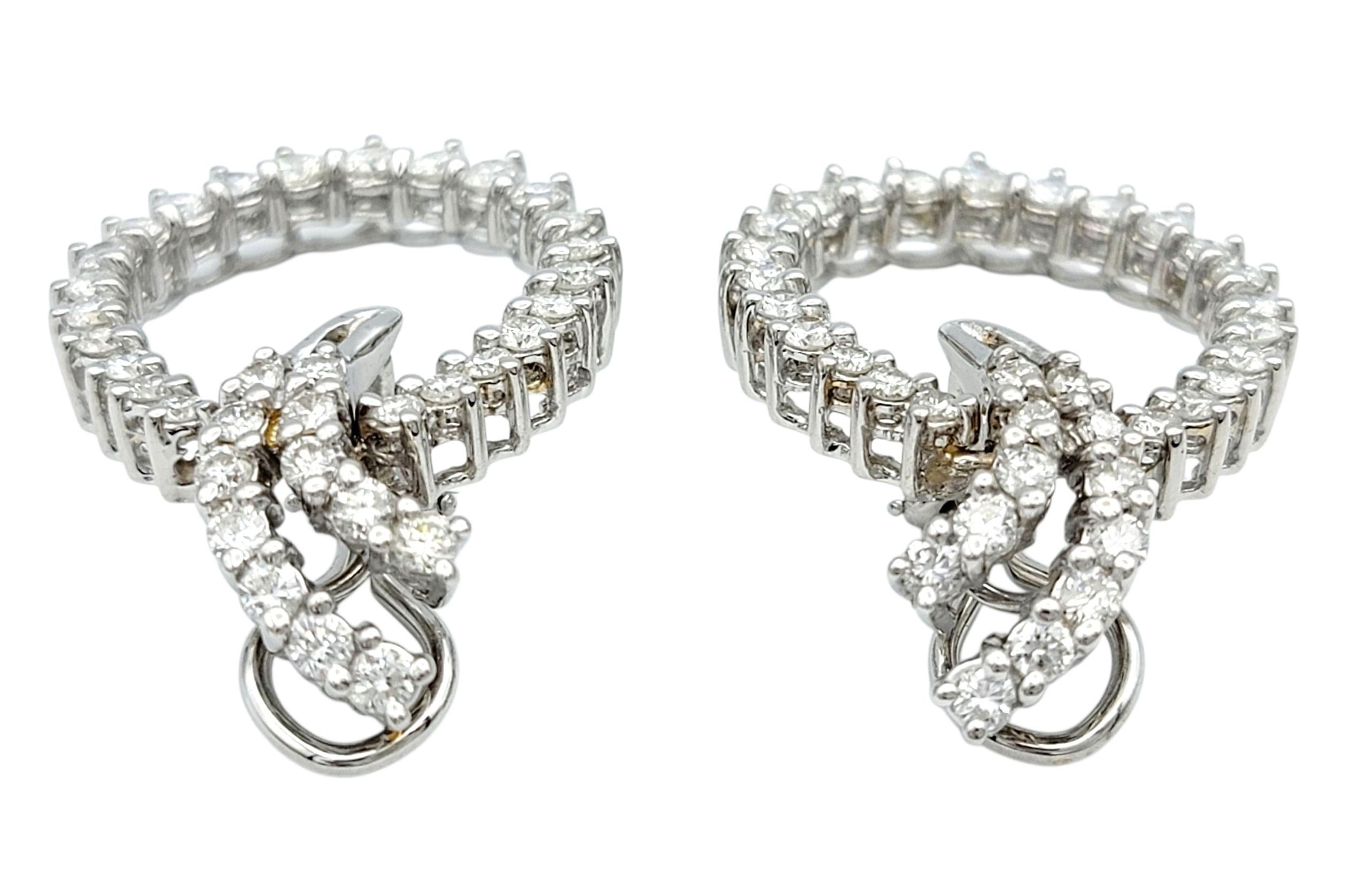 Estos deslumbrantes pendientes de diamantes están elaborados en oro blanco de 14 quilates y presentan impresionantes diamantes de talla brillante. Los diamantes están dispuestos en un diseño de bucle continuo, proporcionando brillo desde todos los
