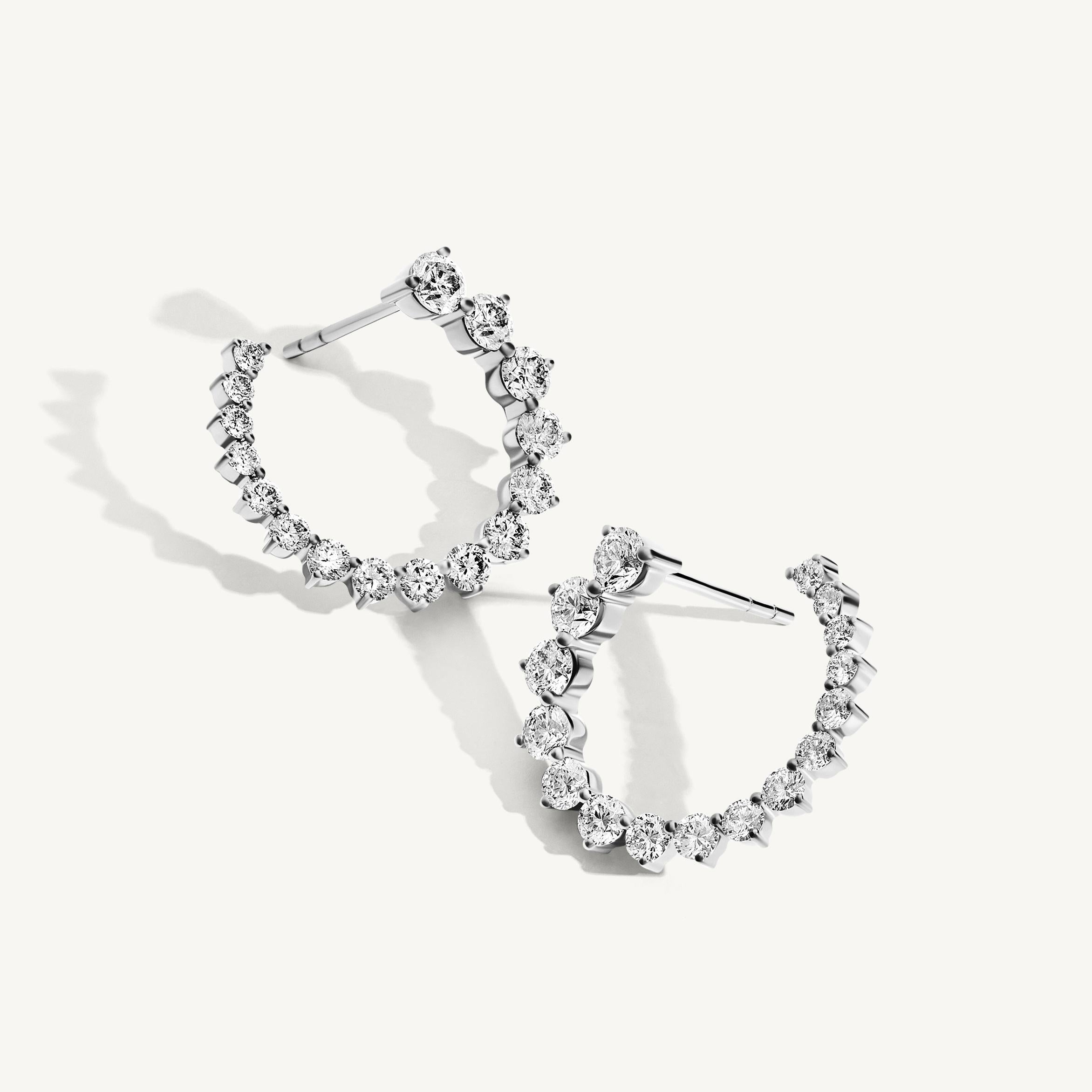 Showcasing 16 natural graduating round brilliant cut diamonds, the Graduating Round Diamond Open Hoop Earrings form a striking tapered silhouette that exudes timeless elegance. Designed as front-facing hoops, each earring frames the face with