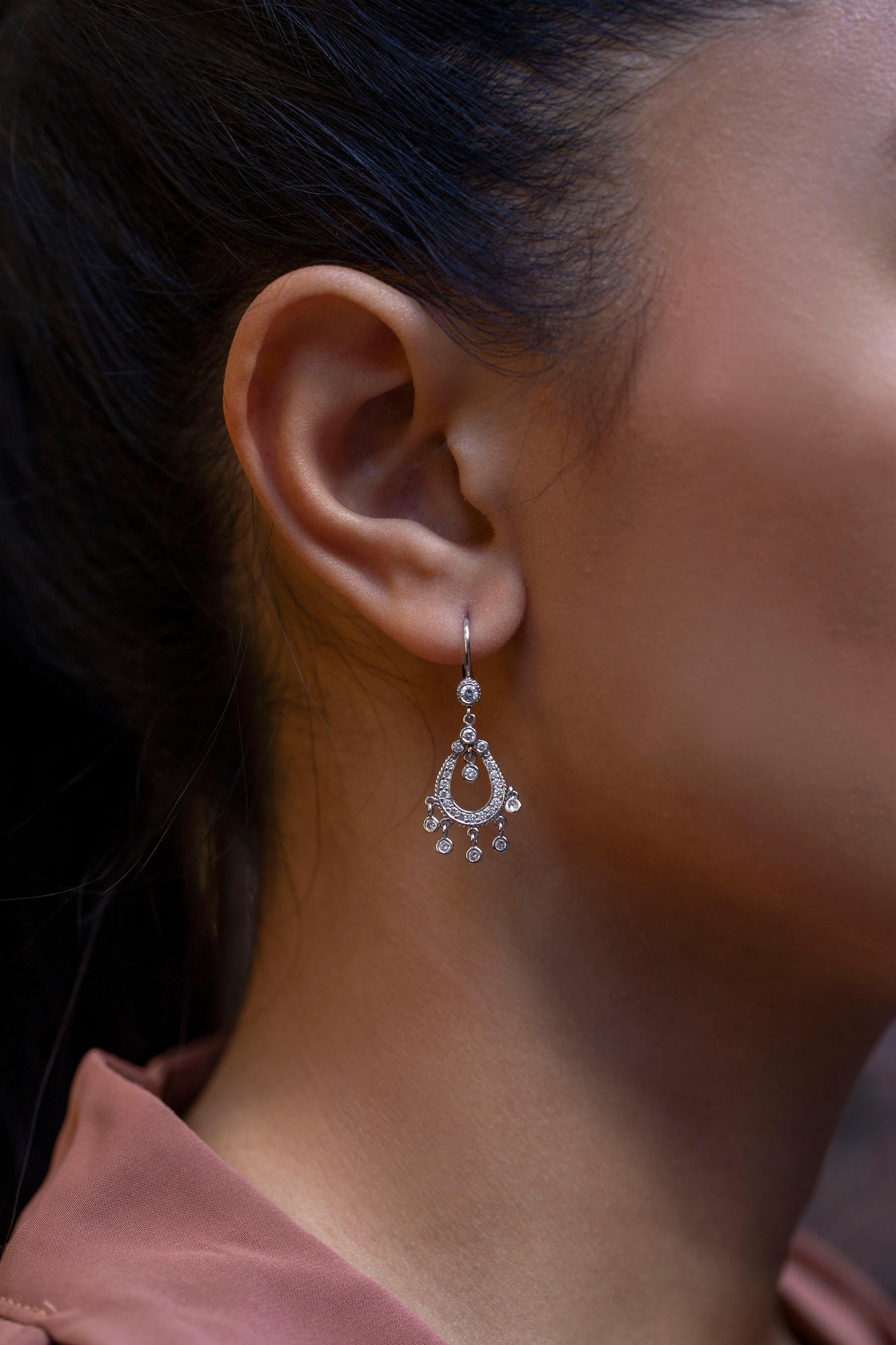 An elegant dangle earrings features 0.68 carats of brilliant round diamonds pave set in a horse-shoe shape with twisted rope edges. Accented by five bezel set round diamond fringes. Made in 18K White Gold. 

Style available in different price