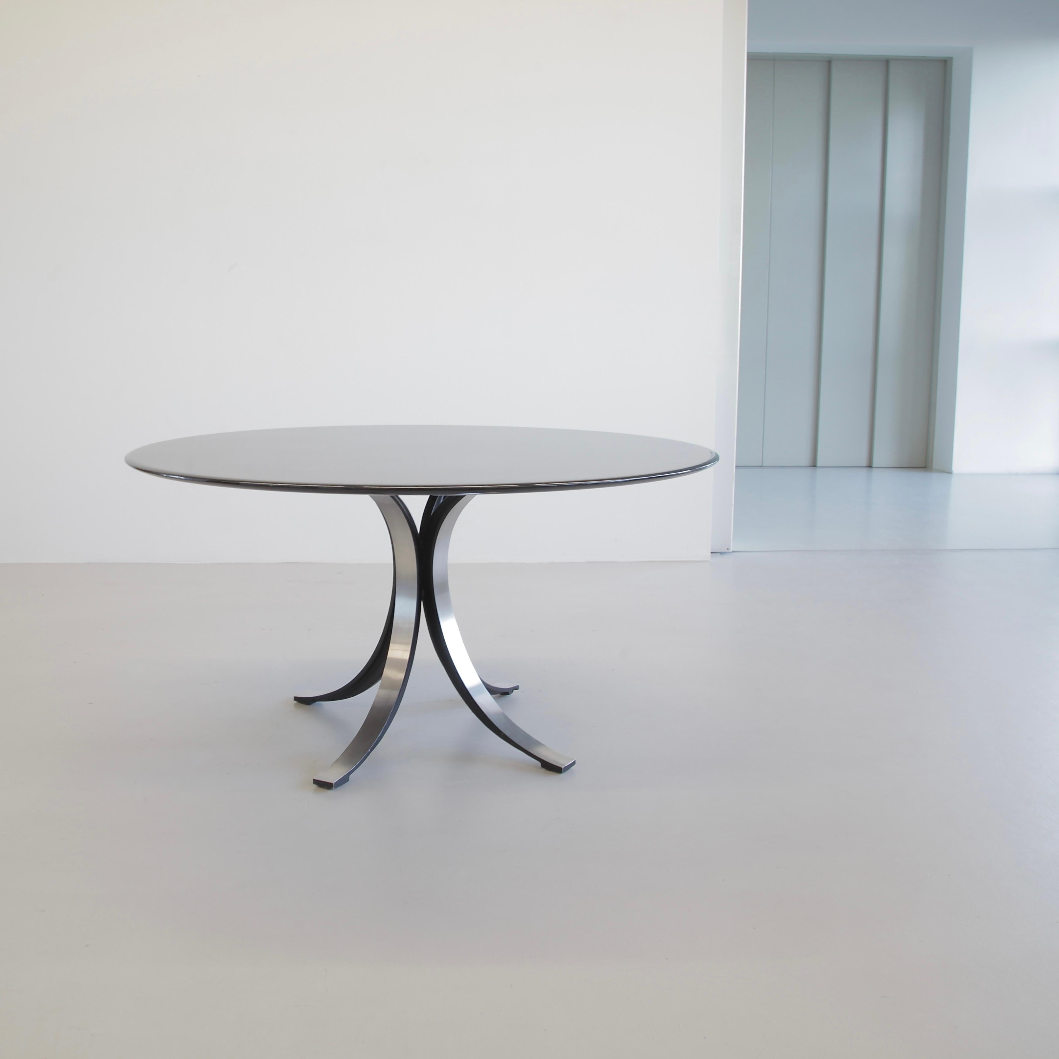 Round dining table (T69A), designed by Osvaldo Borsani and Eugenio Gerli in 1963/64. Produced by TECNO.

Brushed metal base with the inner sides finished in matt black enamel. Original black lacquered wooden round table top. TECNO label on