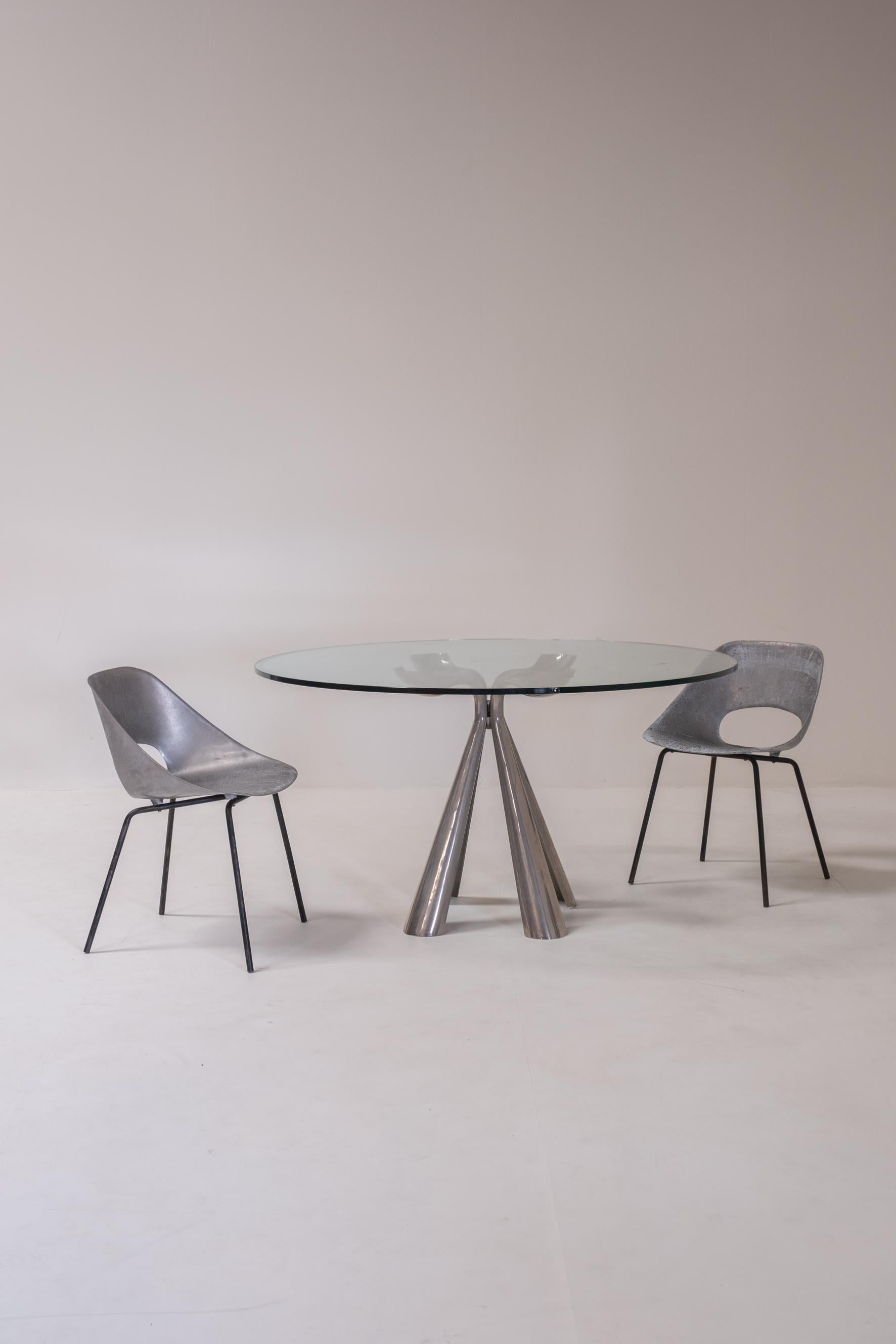 Striking round table designed by Vittorio Introini for Saporiti. The piece features a sculptural, flower-like pedestal base with four fluted, petal-shaped supports in polished metal that rise to cradle a thick circular glass top. The interplay of