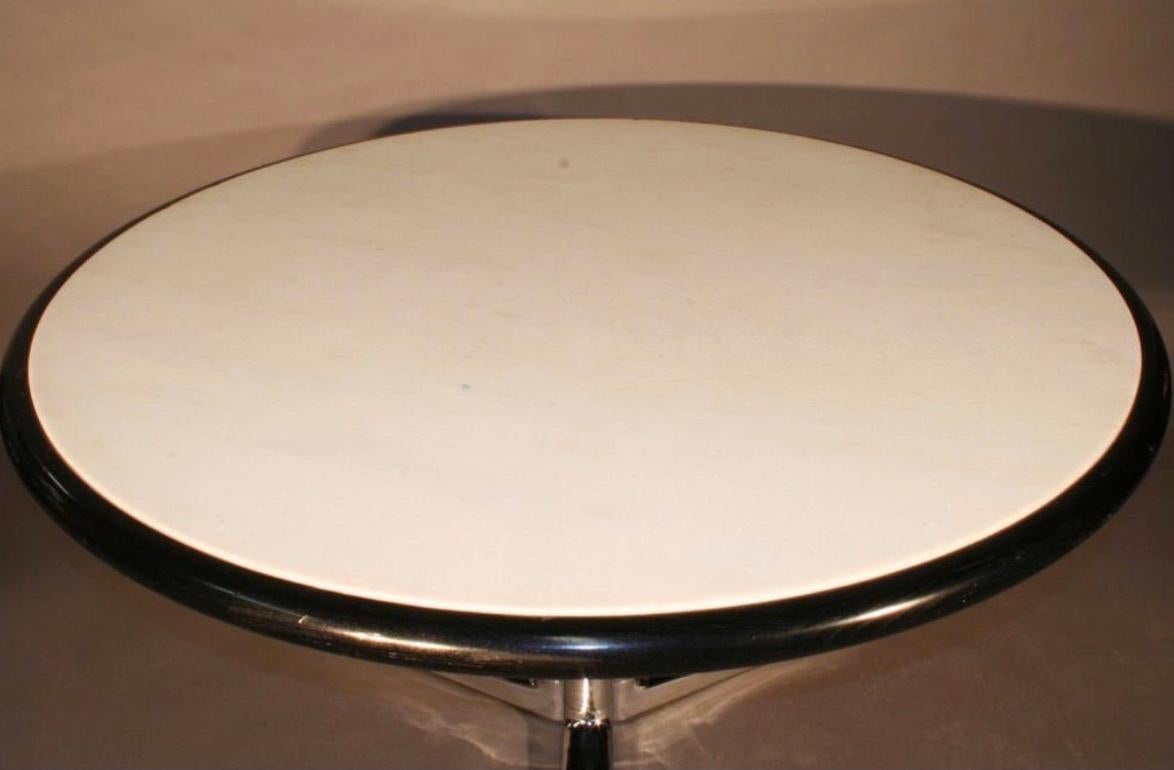 Der runde Warren Platner Esstisch hat eine abgeschrägte Kante aus ebonisierter Eiche, die die weiße Marmorplatte umschließt. Beide werden von einem dreibeinigen verchromten Metallfuß getragen. Insgesamt ist der Tisch sehr stabil und in einem sehr