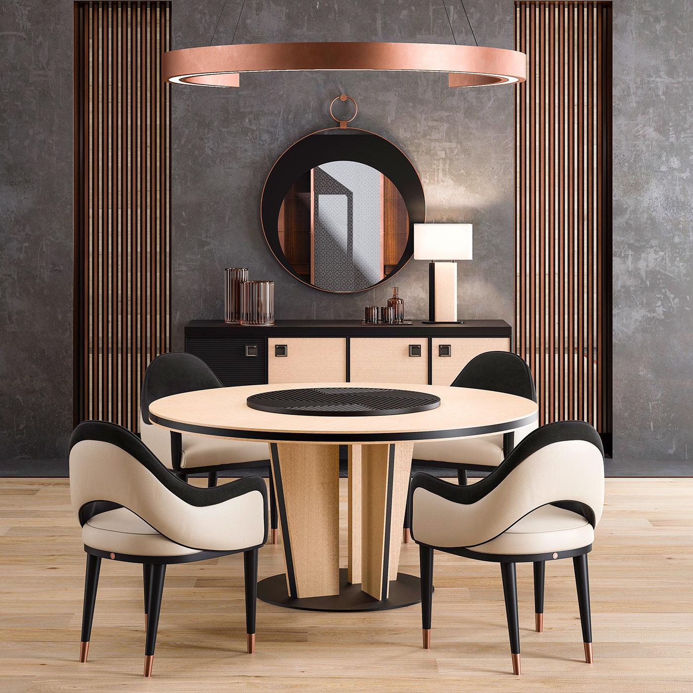 Marked by a two-tone design, this stunning round table is crafted on beige eucalyptus veneer with black-lacquered inserts. The base sits on a round black-finished metal plate and is made up of four legs set closer to the center to form a pillar-like