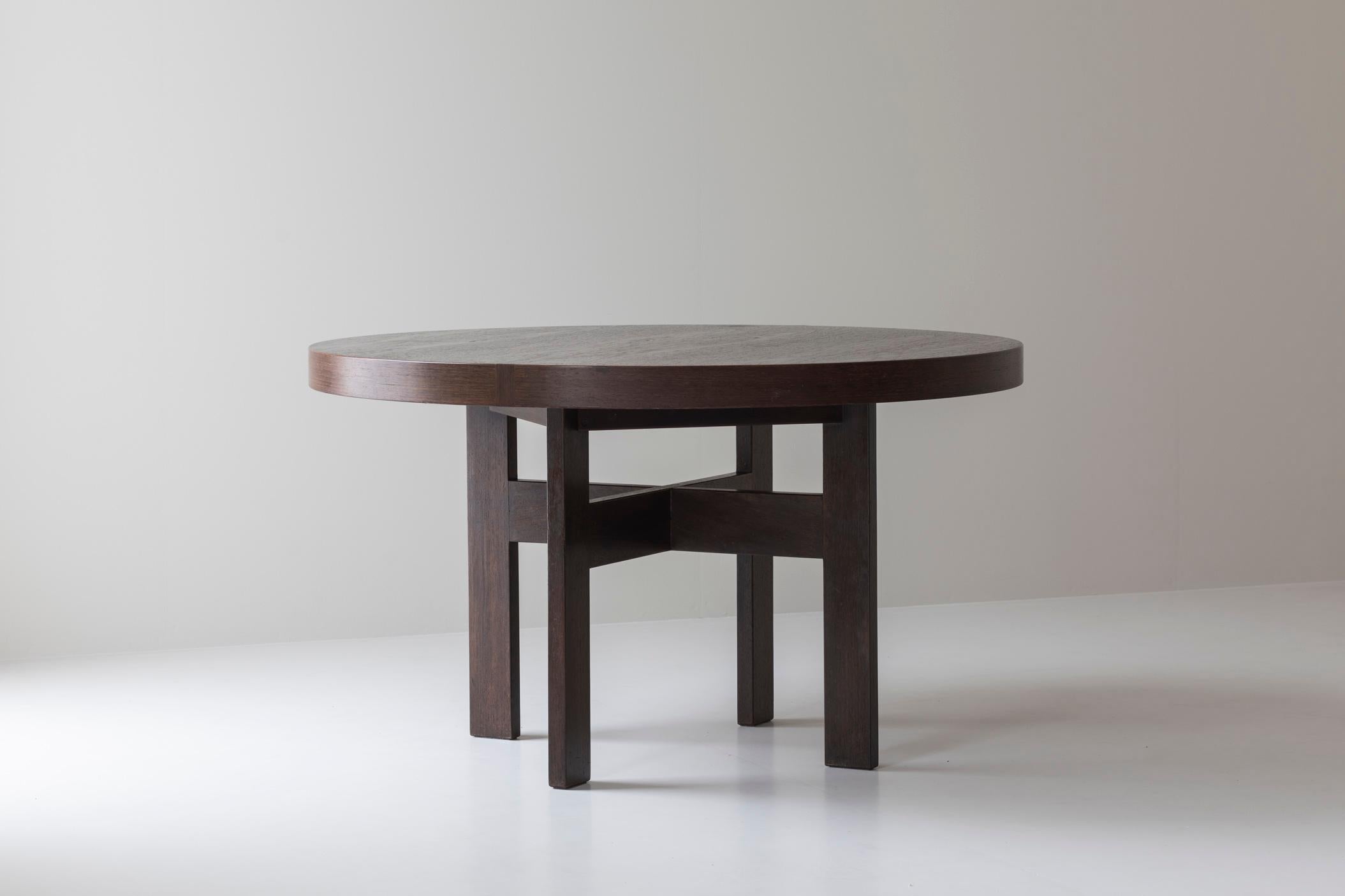 Round dining table, Dutch design from the 1960s. This table has a wengé veneer tabletop, supported by a cross-shaped based of solid wengé legs. The continuity of the strips on the side of the table is interrupted by two pieces of veneer which are