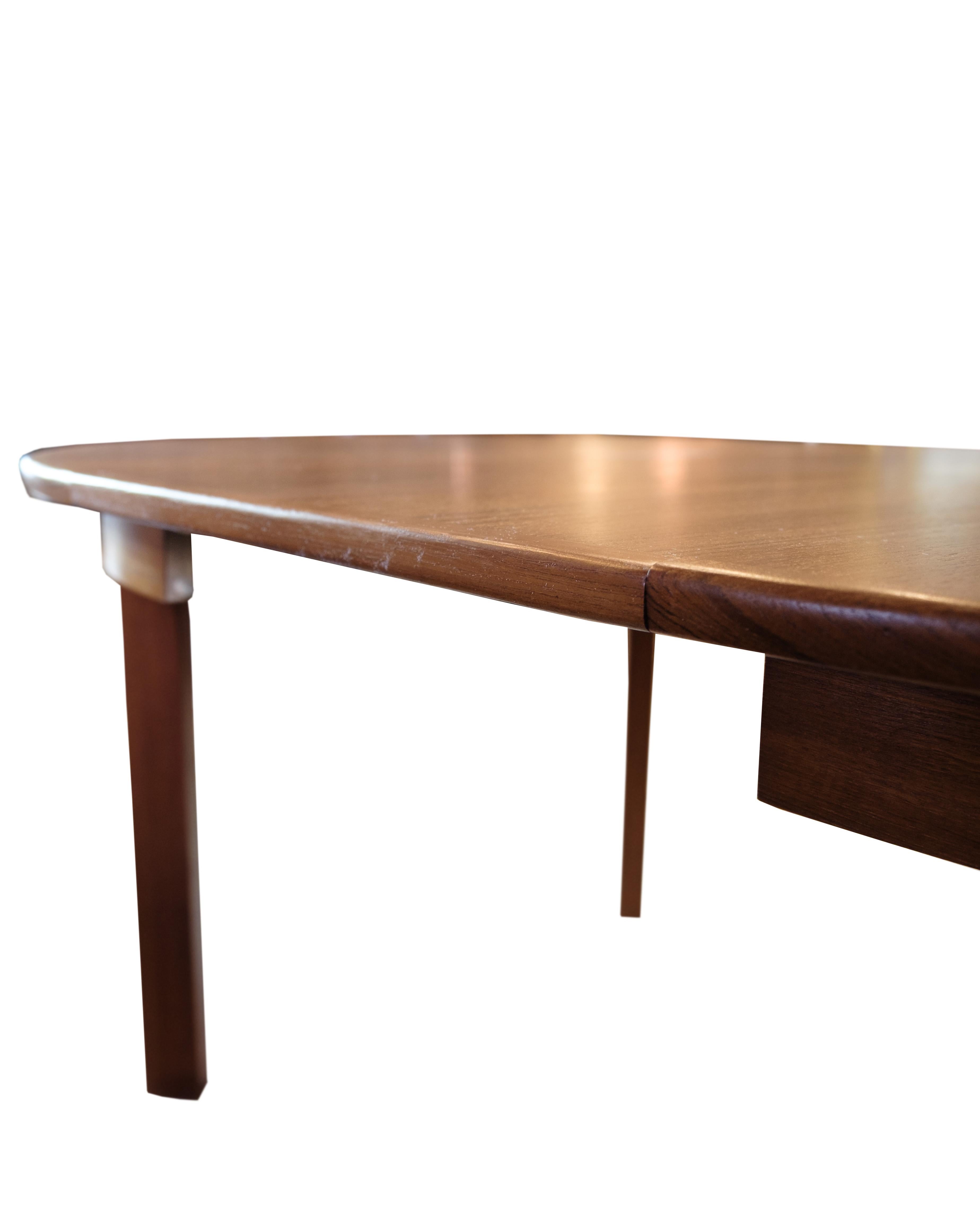 Tavolo da pranzo rotondo degli anni '60 in teak con due prolunghe. Il tavolo ha un'espressione classica e funzionale, con gambe dritte e un profilo dei bordi semplice. Le prolunghe permettono di espandersi in modo flessibile e rendono il tavolo