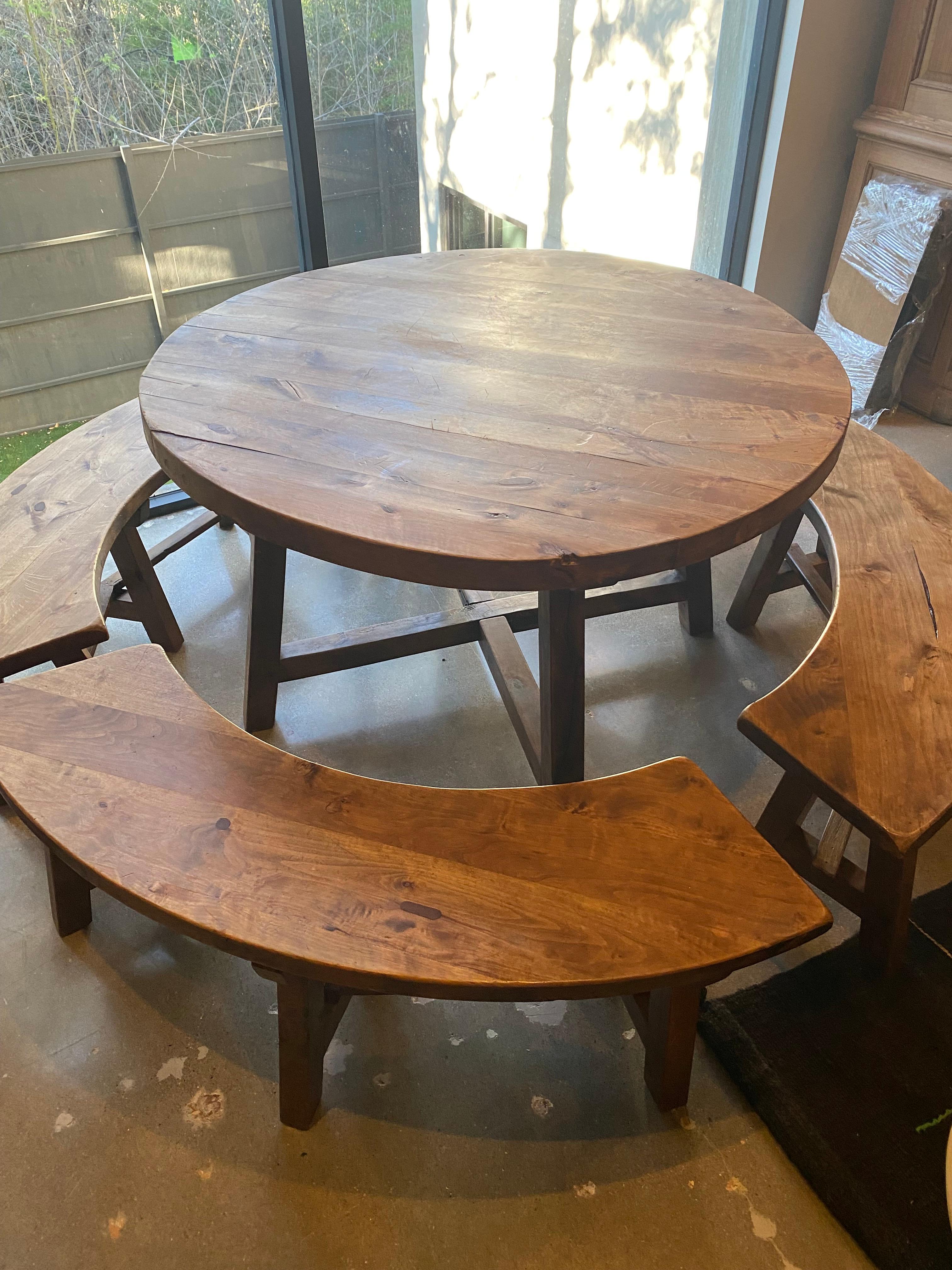 Mid-century Chalet style round dining table with four matching benches. Hand crafted in solid hardwood (Elm?) with trestle bases and forged iron hardware on table. Indicative of the rustic mountain style made for French Alps estates in the