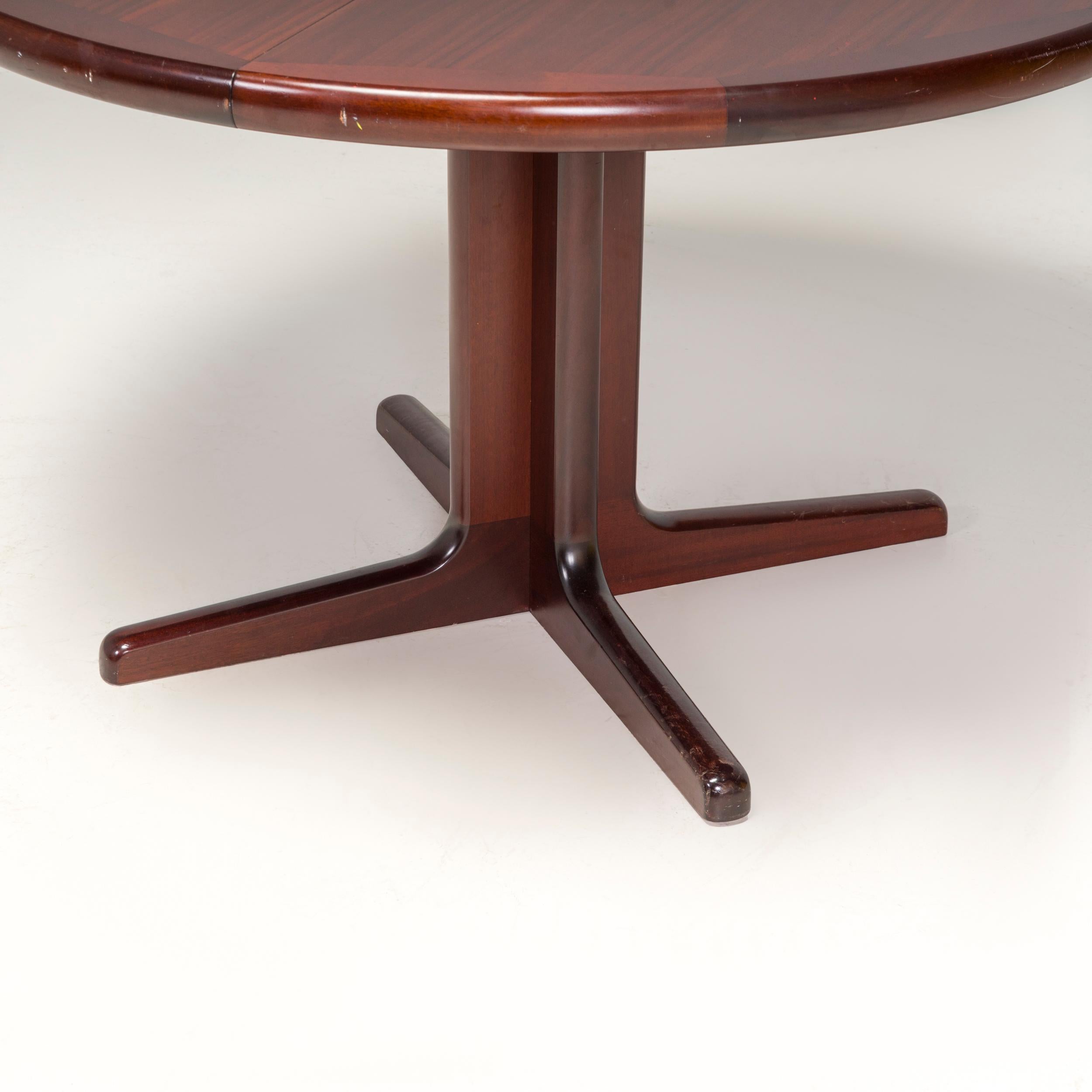 This dining table is a classic example of Mid-Century Modern design.

Constructed from rosewood, the dining table has a circular table top sitting on two sets of v-shaped legs, which create a four star base when not extended.

Two additional