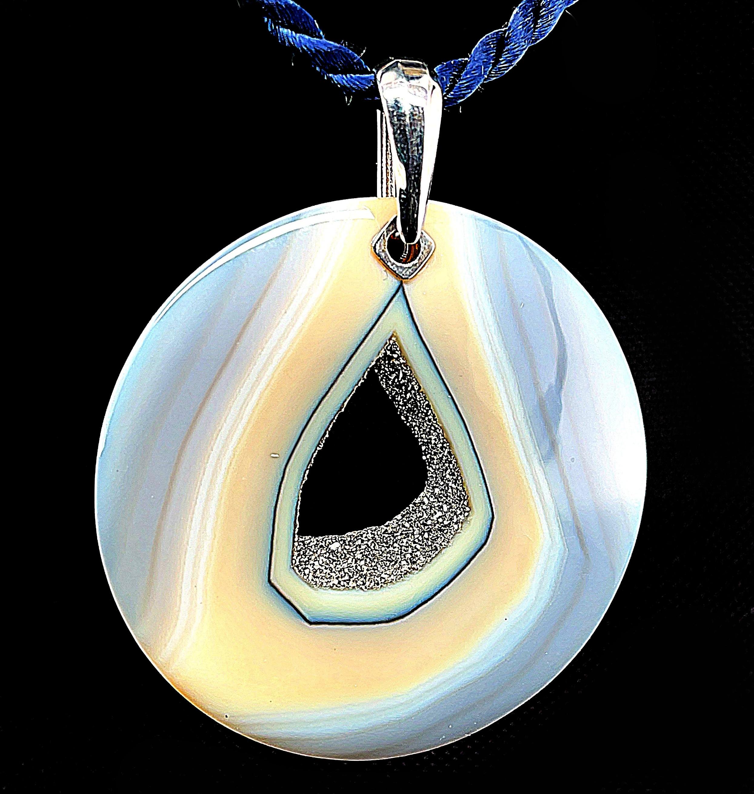 A large, polished druzy quartz agate is suspended from a bright 14k white gold bail in this stunning statement pendant. Druzy agate is a natural gemstone and this particular gem has beautiful color striations in beige and bluish gray tones that will