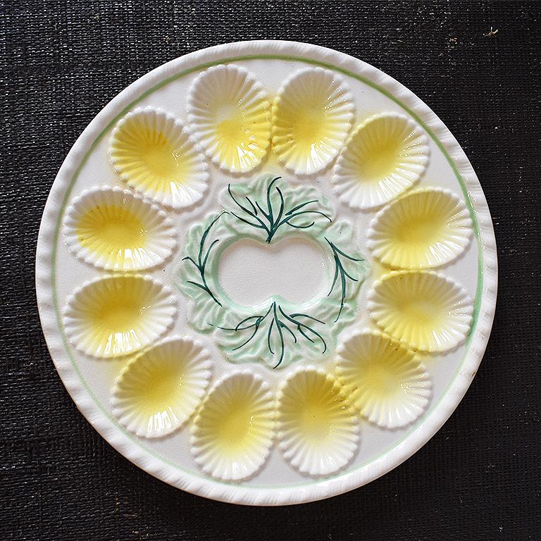 Round Yellow and green oyster or egg serving platter. Beautiful cream white plate with green detailed center and edge. Each dip is yellow in color and in a seashell shape. At the center, is a space for an open oyster shell or dipping sauce. 

This