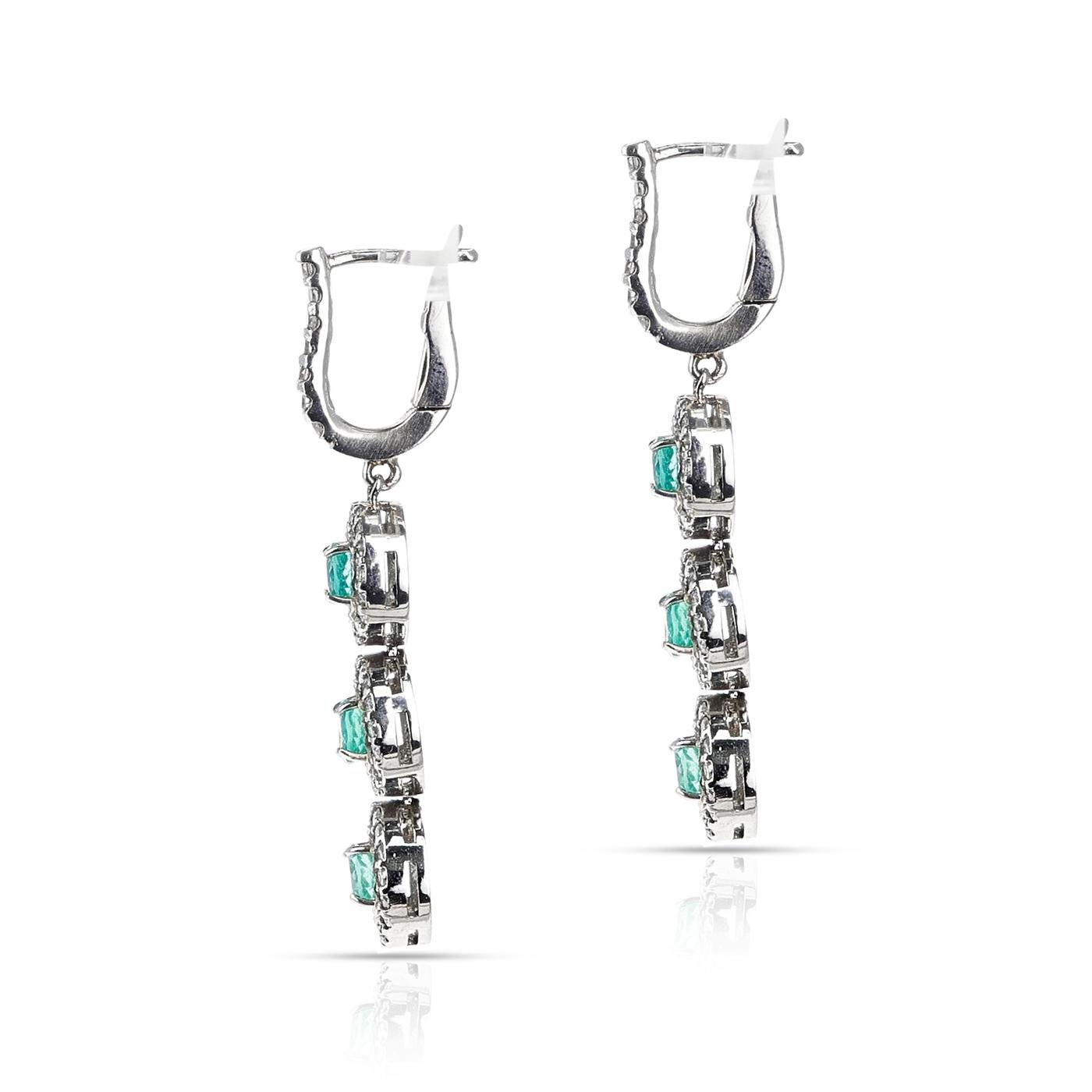 A pair of Three Round Emerald and Diamond Dangling Earrings made in 14 Karat White Gold. The weight of the diamonds is 1.25 carats. The length of the earrings is 1.50 inches. The total weight of the earrings is 6.95 grams. 