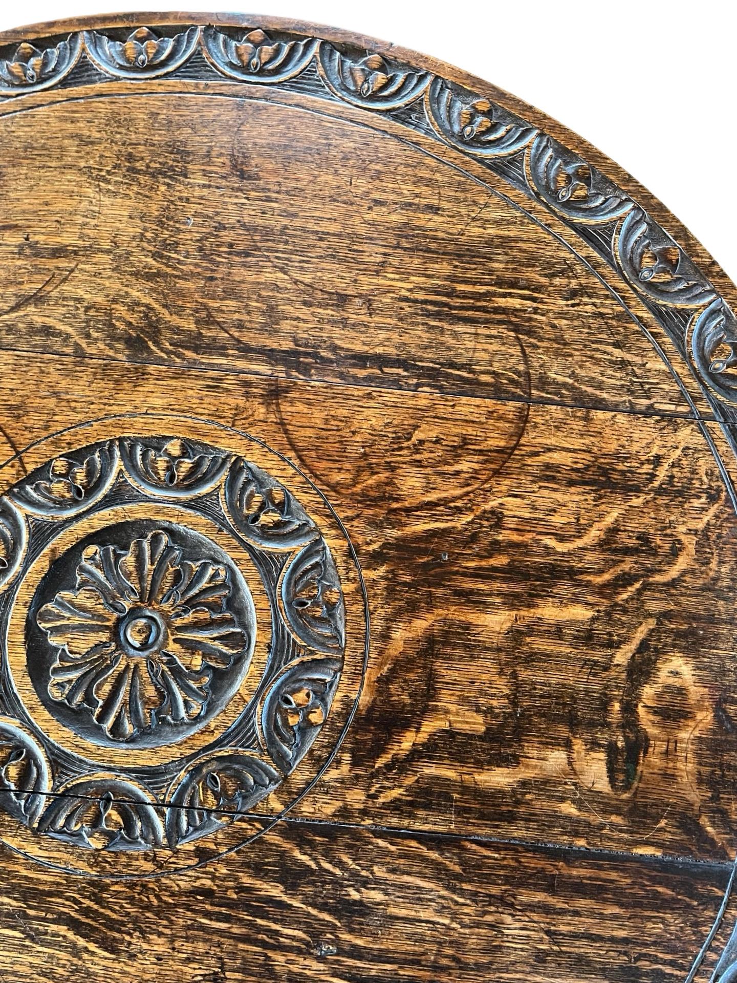 Flip top round side table hand-made in England in the early 1800s using oak. The table sits on tripod legs, one of which may have been restored and replaced in the past. The table latches flat at 71cm making it a great height for a small enter