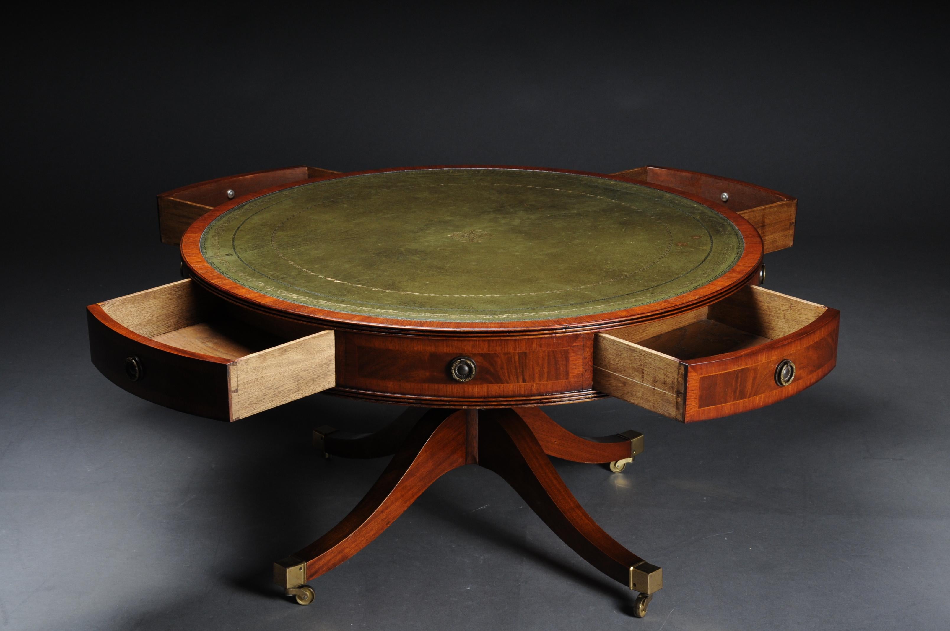 Round English coffee table Chesterfield table, circa 1900

Solid wood, round drawer with four drawers. Classic green leather plate with gold embossing. Table top standing on four legs ending with brass roller feet. Victorian England, circa