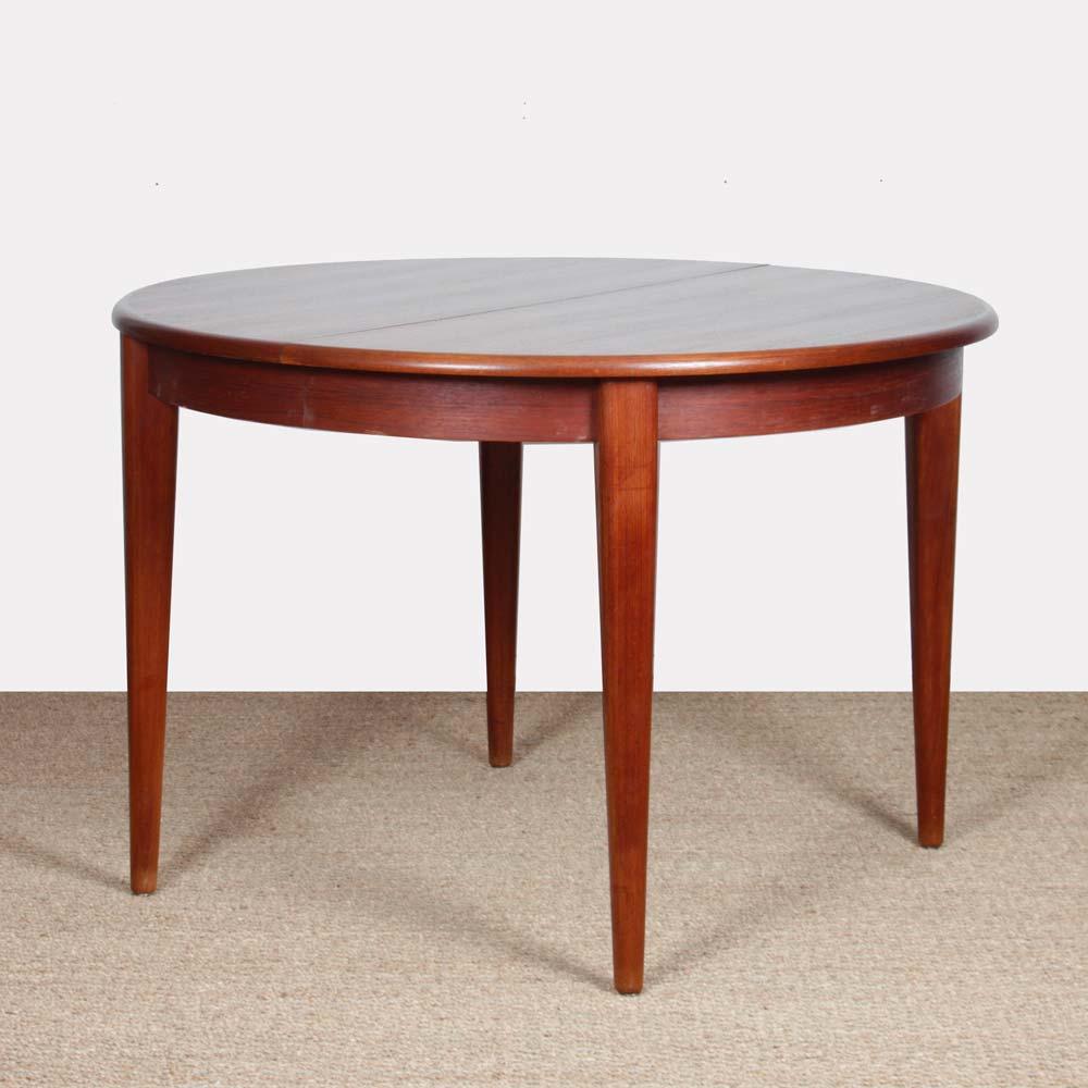 This round dining table in teak is extendable. It includes a 36 cm extension leaf. It is a Scandinavian design from the 1960s. This table is in good vintage condition. The top is restored.