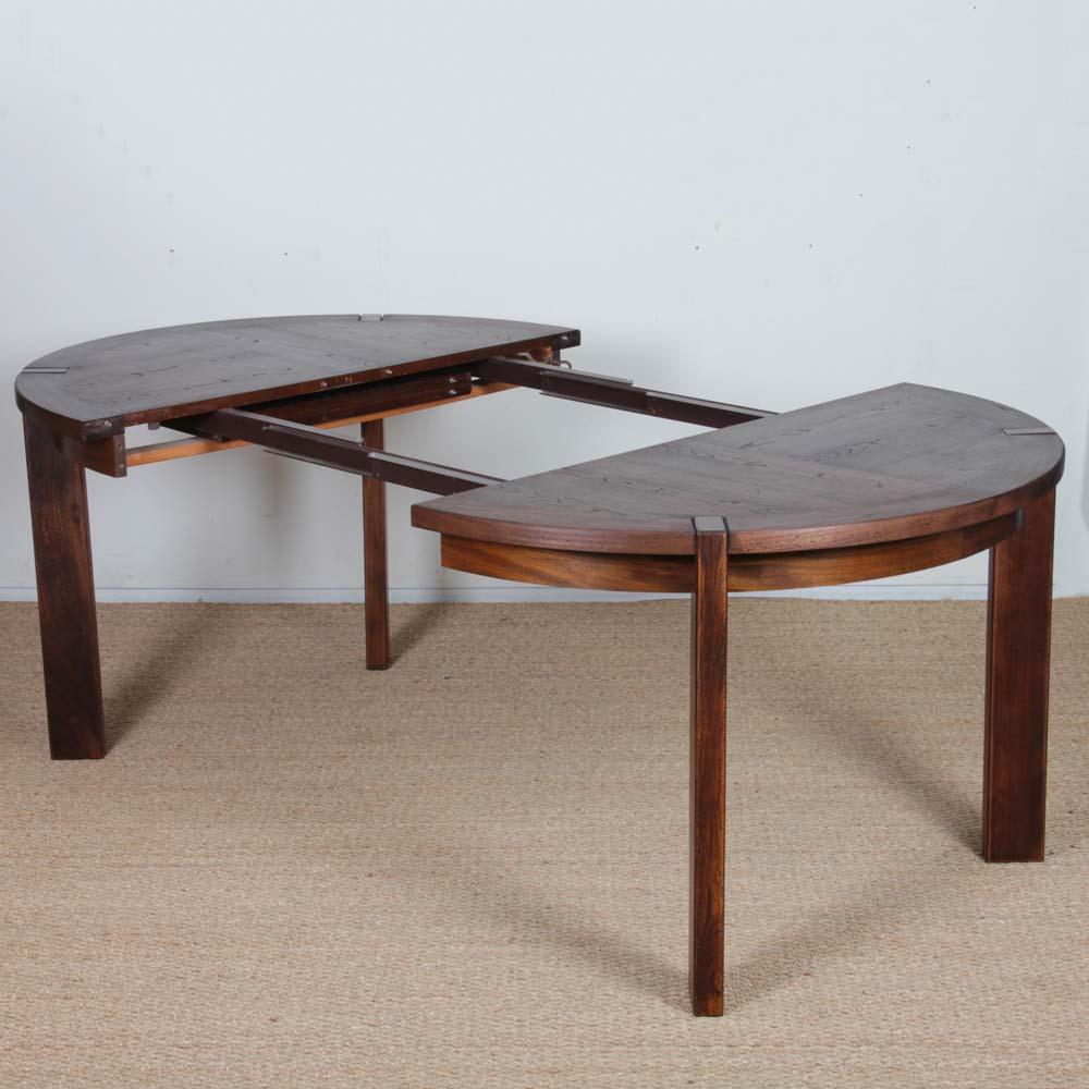 Questo tavolo da pranzo rotondo in legno è allungabile. È stato prodotto da Monopoly negli anni '70. Realizzato in Francia, ha due prolunghe incorporate (41,5 cm ciascuna) che si nascondono discretamente sotto il piano. La parte superiore e le
