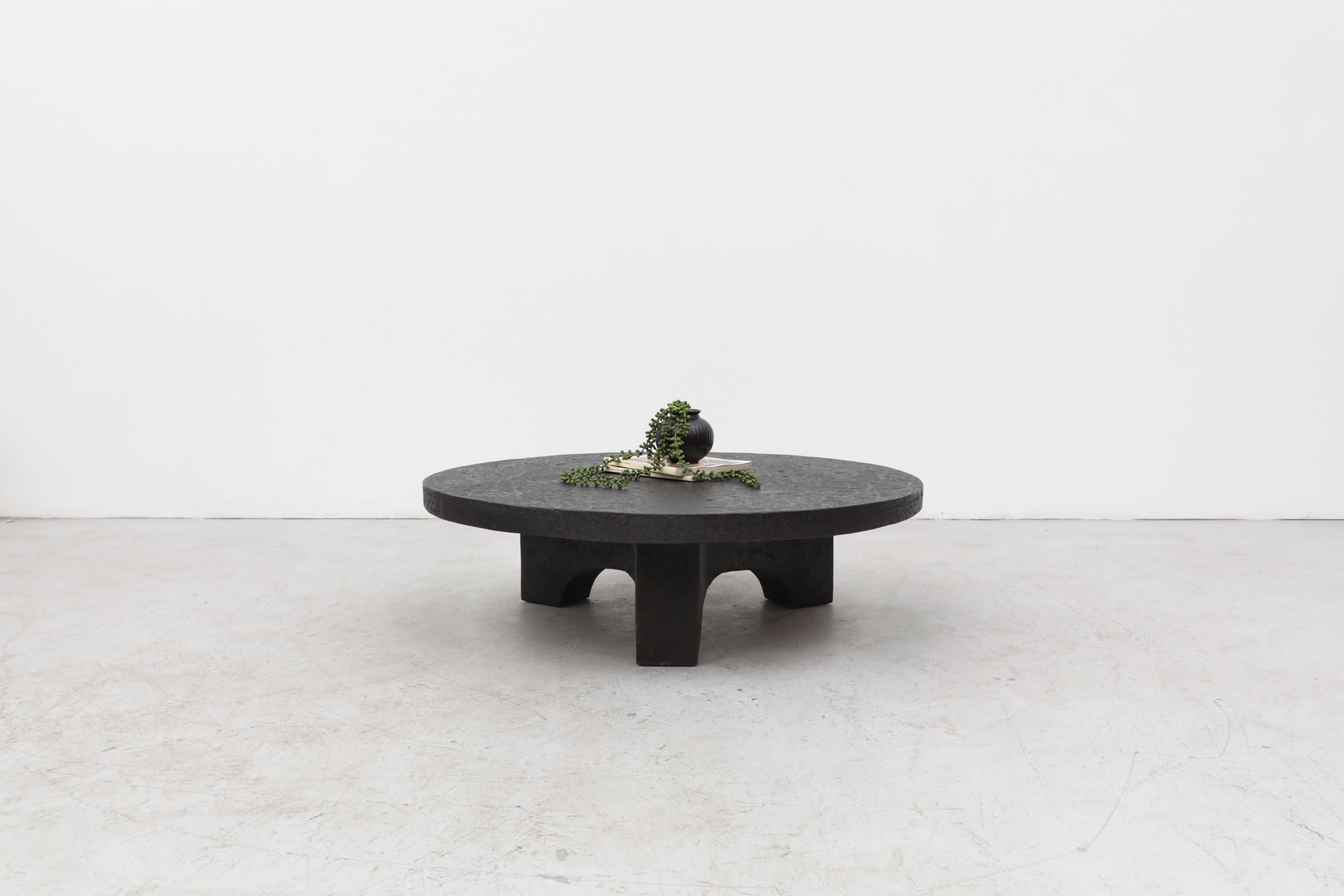 Round faux lava stone coffee or side table with arched base made of heavy cast resin and in original condition with wear consistent with its age and use. Other faux lava stone tables are available and listed separately (T442).