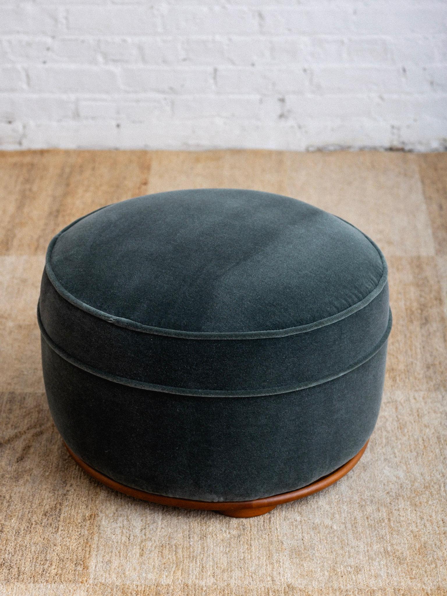A French Art Deco ottoman. Newly upholstered in a dark teal mohair retaining the original inner spring suspension. Wood base with round disc feet. French import sticker remains.