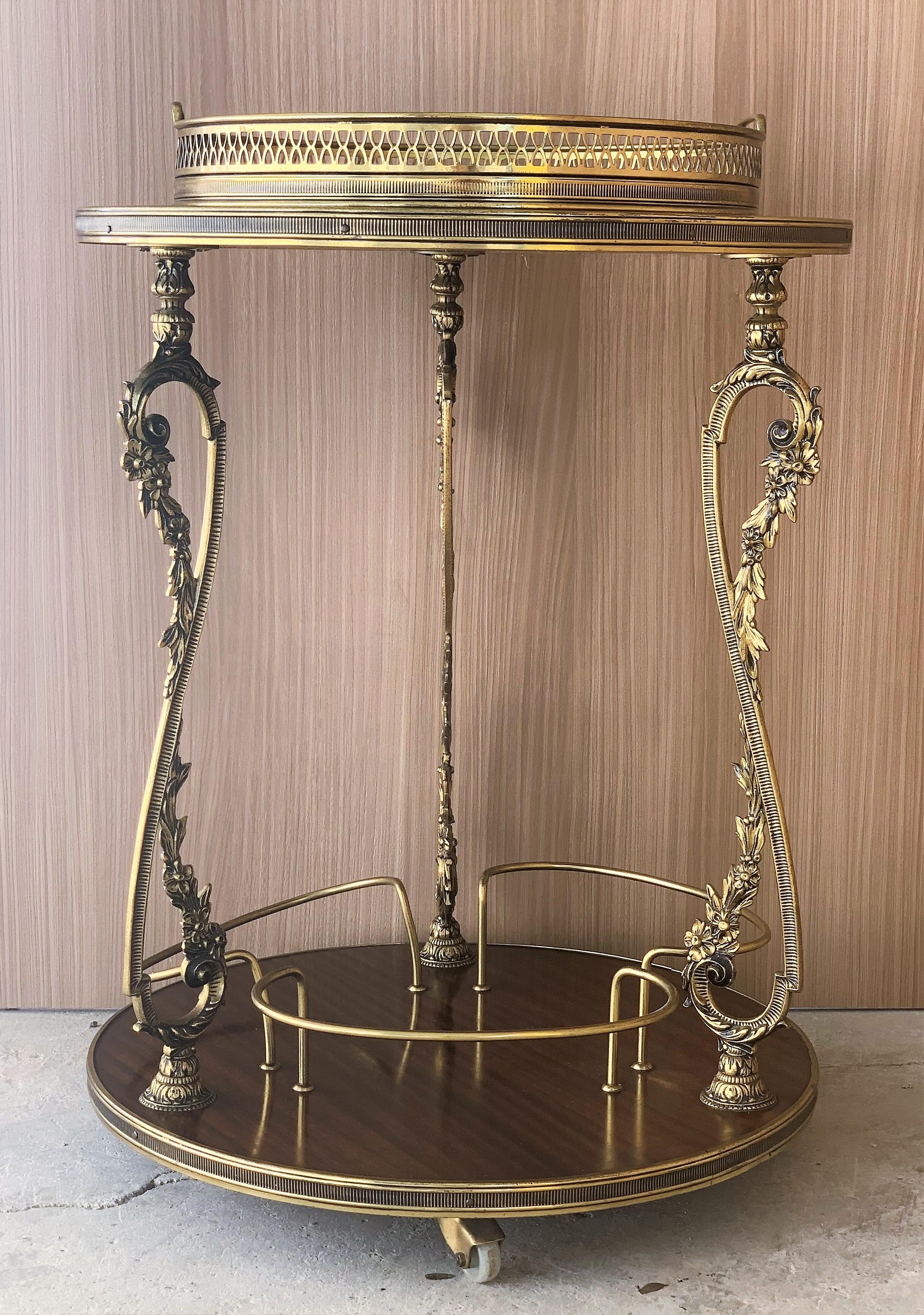Elegant round bar cart made of bronze, mahogany veneer and glass in 1930s, France, attributed to Maison Baguès. The cart features 2 mahogany veneer tops with brass galleried edges, the serving tray in brass and clear glass is removable.