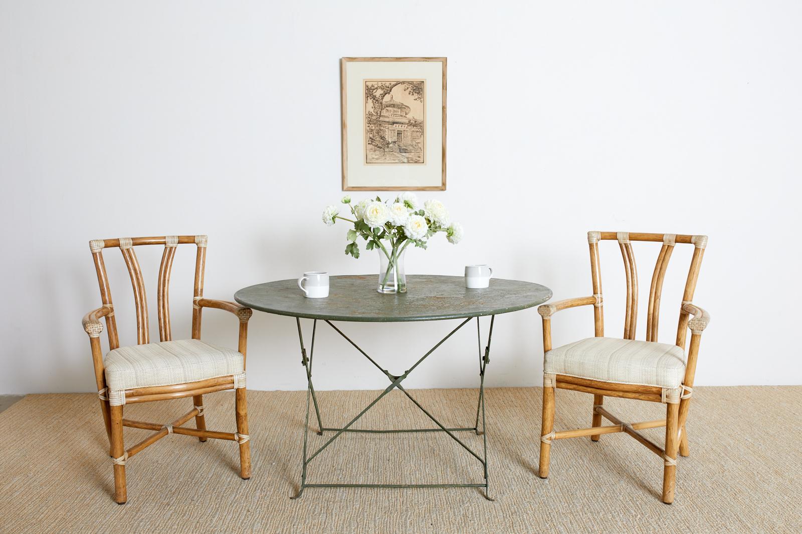 Early 20th century round French iron garden table or dining table featuring a bistro style folding frame. Handcrafted with a beautifully patinated metal finish with an old lacquer patina. Easily folds flat for storage and locks into place when open.