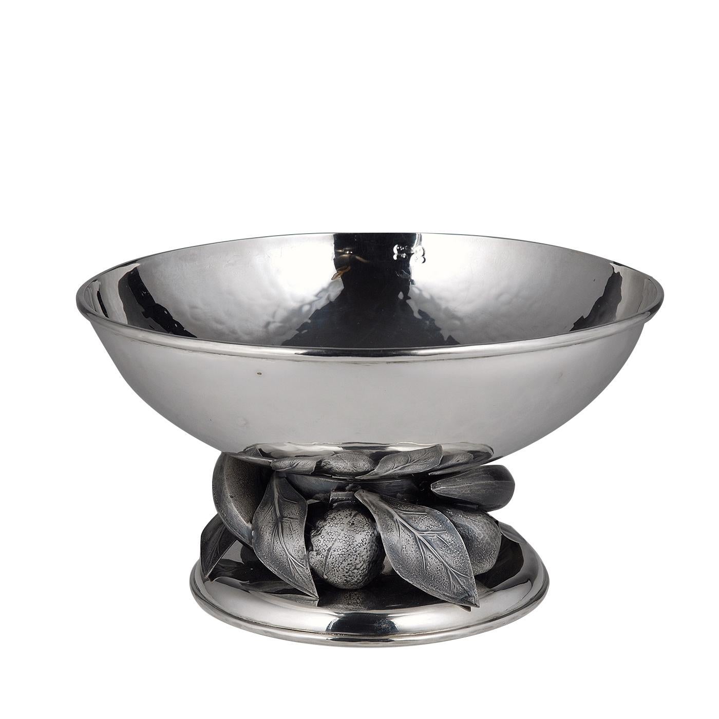 This exquisite fruit bowl is a magnificent example of expert artisanal craftsmanship and elegant design. The round shape of the piece rests on a round base adorned with a series of fruits and leaves that support the body with its lightly-textured
