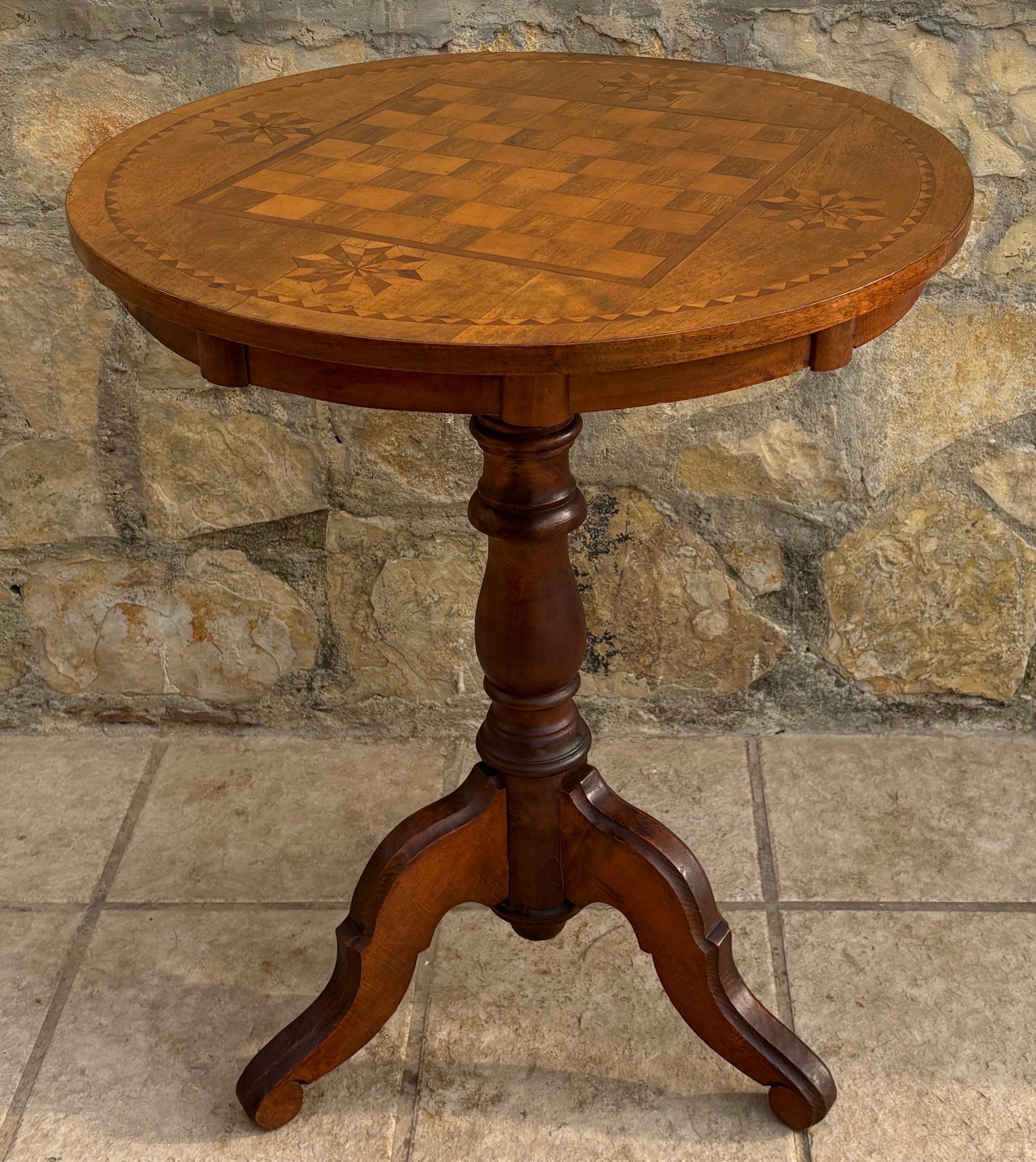 Charming mid-20th century Spanish game table featuring a beautifully inlaid chessboard top. The circular surface displays geometric marquetry motifs and a decorative border, all executed in warm walnut-tone wood that highlights the natural grain and