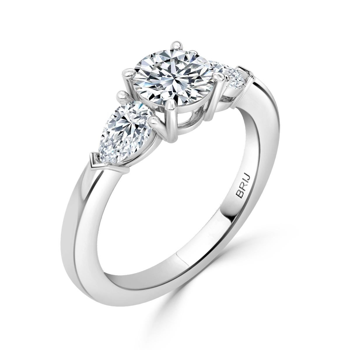 Simple, Classic 3 Stone Diamond engagement ring. Accented with 2 Pear cut GIA Diamonds along the shank  in a 18k White Gold setting. 
GIA certified round center stone 0.80 CT
GIA Certified Side Pear Carat weight 0.64 CT

GIA Certified Diamond