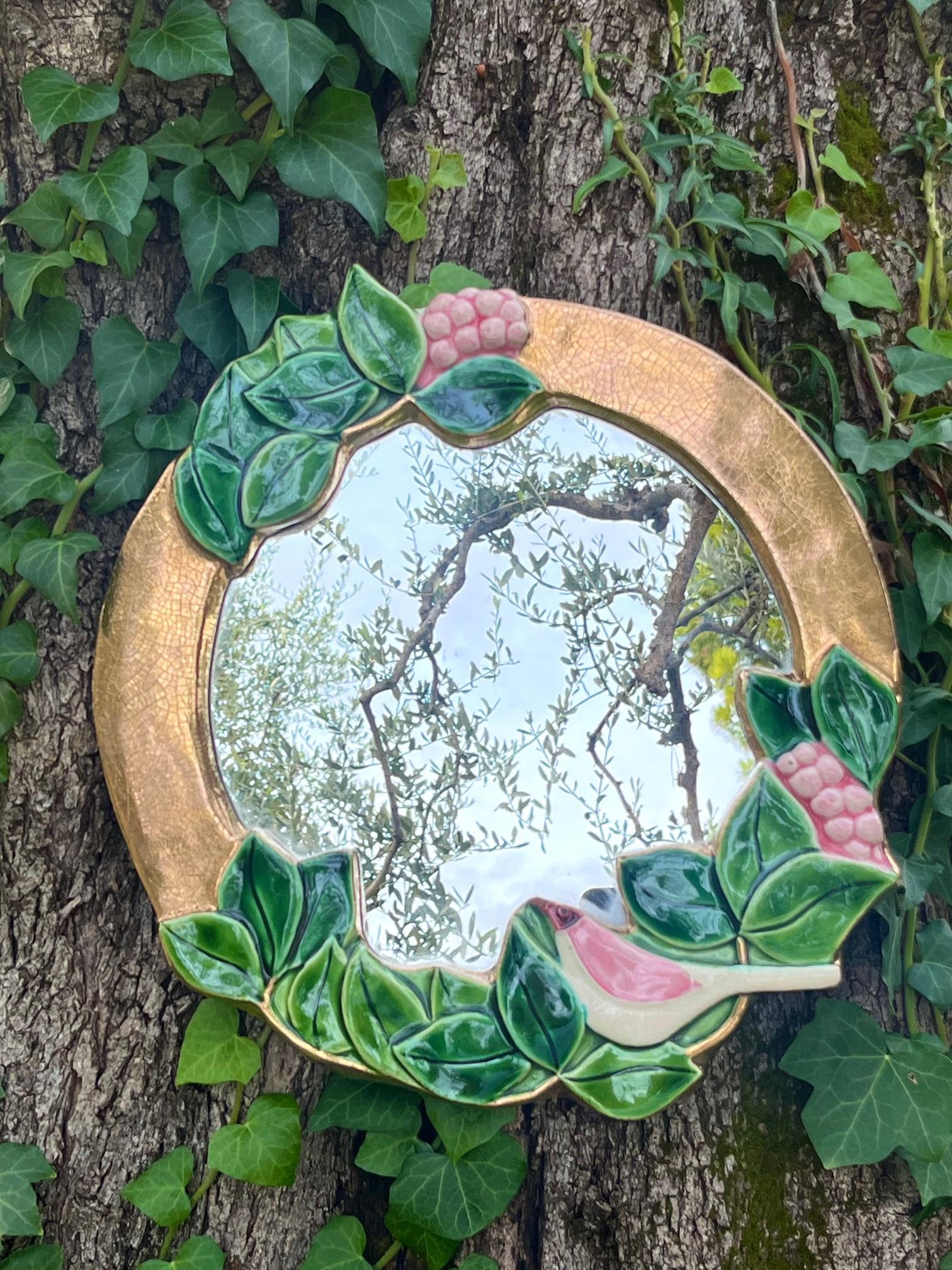  Specchio rotondo con cornice in ceramica.
Terracotta goffrata e smaltata: 
 Cornice dorata con finitura crepata, 
 in parte ricoperto da decorazioni di uccelli, uva e foglie smaltate nei toni del rosa, del bianco e del verde.

Fodera in feltro sul