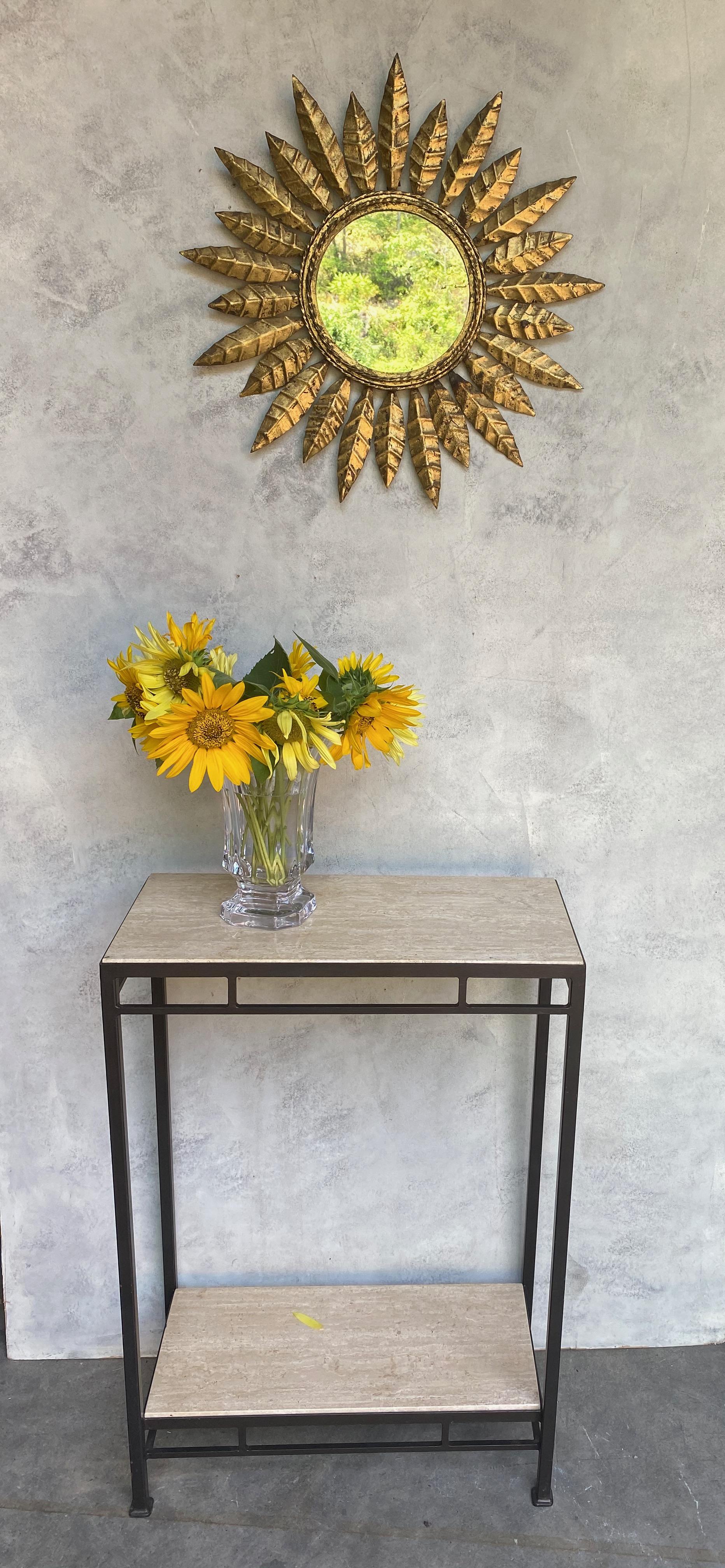 This striking Spanish sunburst mirror, dating back to the 1950s, features a gilt metal frame with a unique design of alternating leaf motifs that radiate from a twisted rope detail. The mirror has been recently updated with a new felt backing,