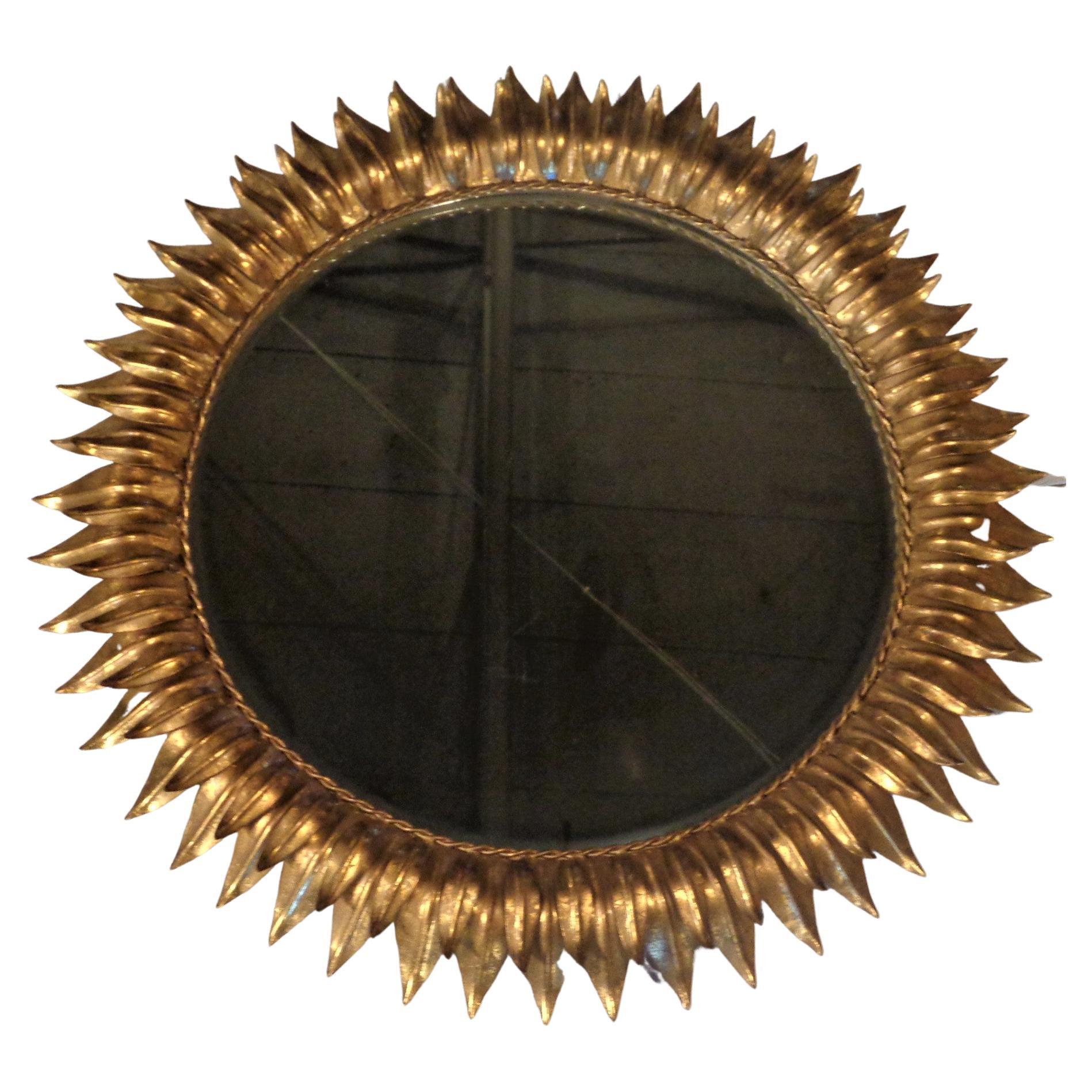Spanish style round gilt metal sunburst mirror. Framework w/ two layers of curved leaves. Interior beveled plate glass mirror. Overall beautiful original bright gilded gold leaf surface. Mirror frame measures 28