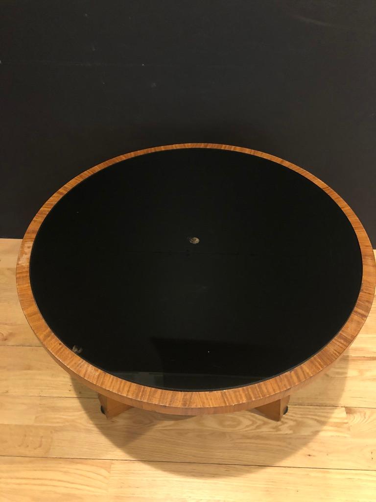 Unusual three plank pedestal round side table. Black glass or mirror inlaid top. Three legs supported by lower round shelf. Could also be used as a coffee or cocktail table.