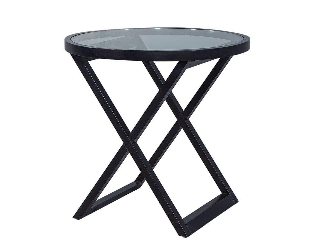 This lacquered table has a cross braced base with an inset tempered glass top. Its piano black finish makes it an elegant piece. It is a portable table which can be used for presenting food and drinks to guests, as a flower vase holder, etc. Its new