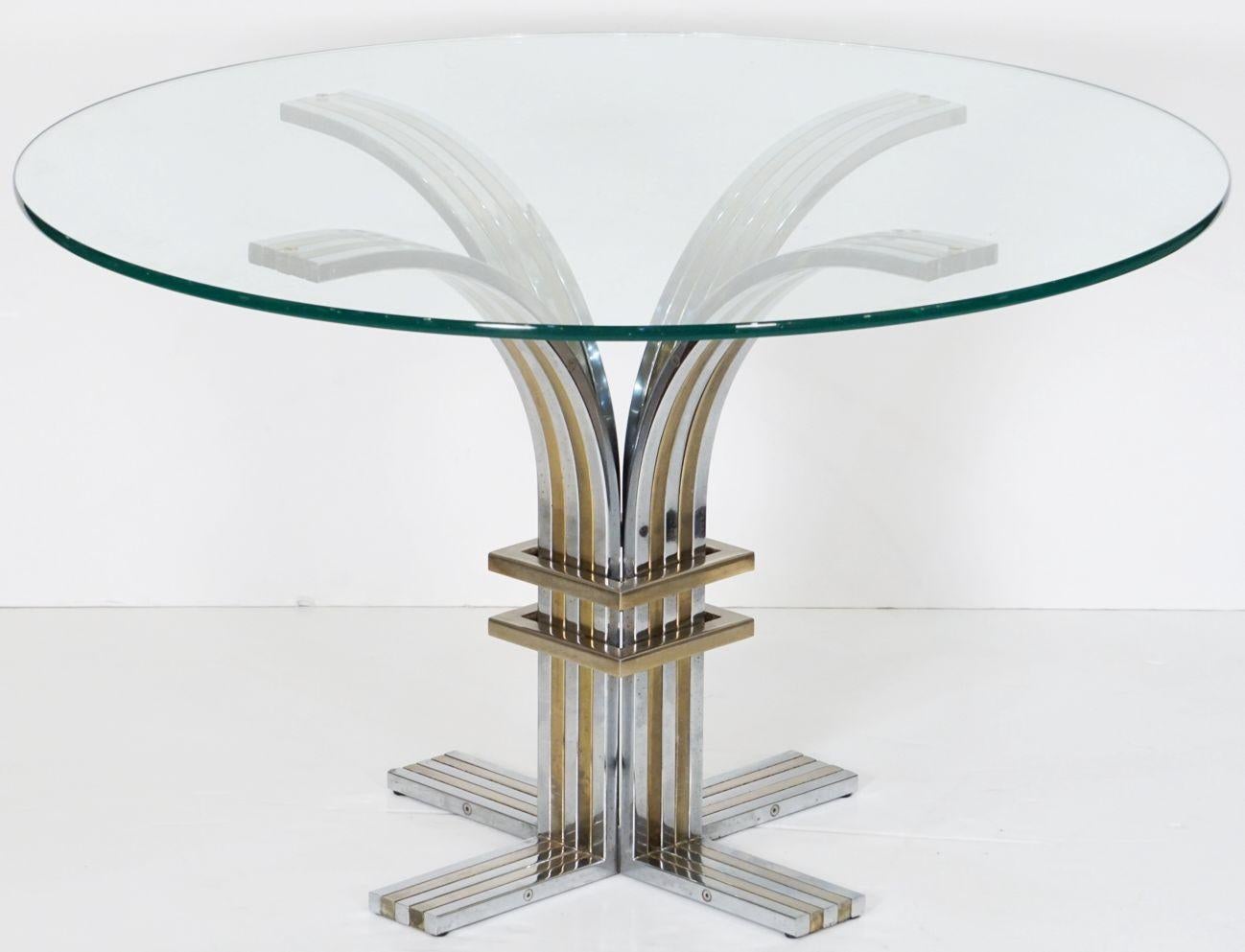 Une belle table de salle à manger ou table centrale moderniste d'Italie, vers 1970, comportant quatre arcs sur une base en forme de croix en métal chromé et en laiton avec un plateau rond en verre, attribuée au célèbre designer italien Romeo