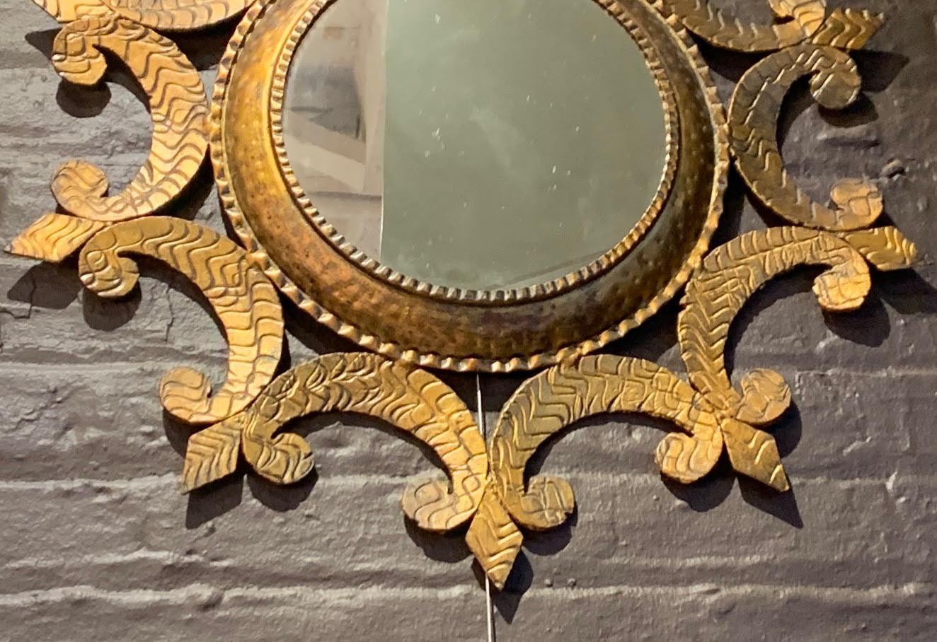 spanischer runder Spiegel mit goldenem vergoldetem Eisenrahmen aus den 1950er Jahren mit dekorativen gehämmerten Details.
Rahmen mit geschwungenem Design.
 