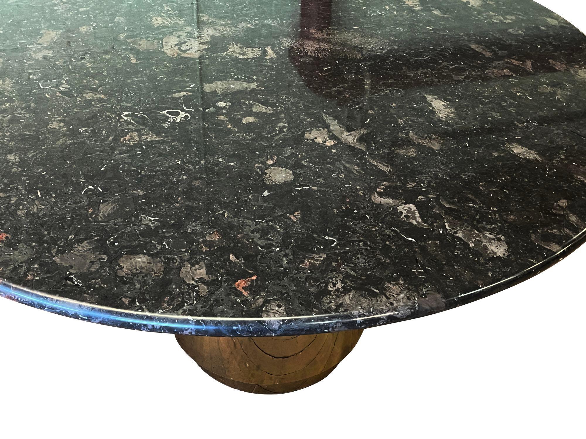 États-Unis, années 1970
Table de salle à manger ronde en granit noir ou en pierre avec un bord arrondi, reposant sur une base cylindrique lestée en laiton. Un look classique avec un glamour moderne.
La partie supérieure repose sur la base sans