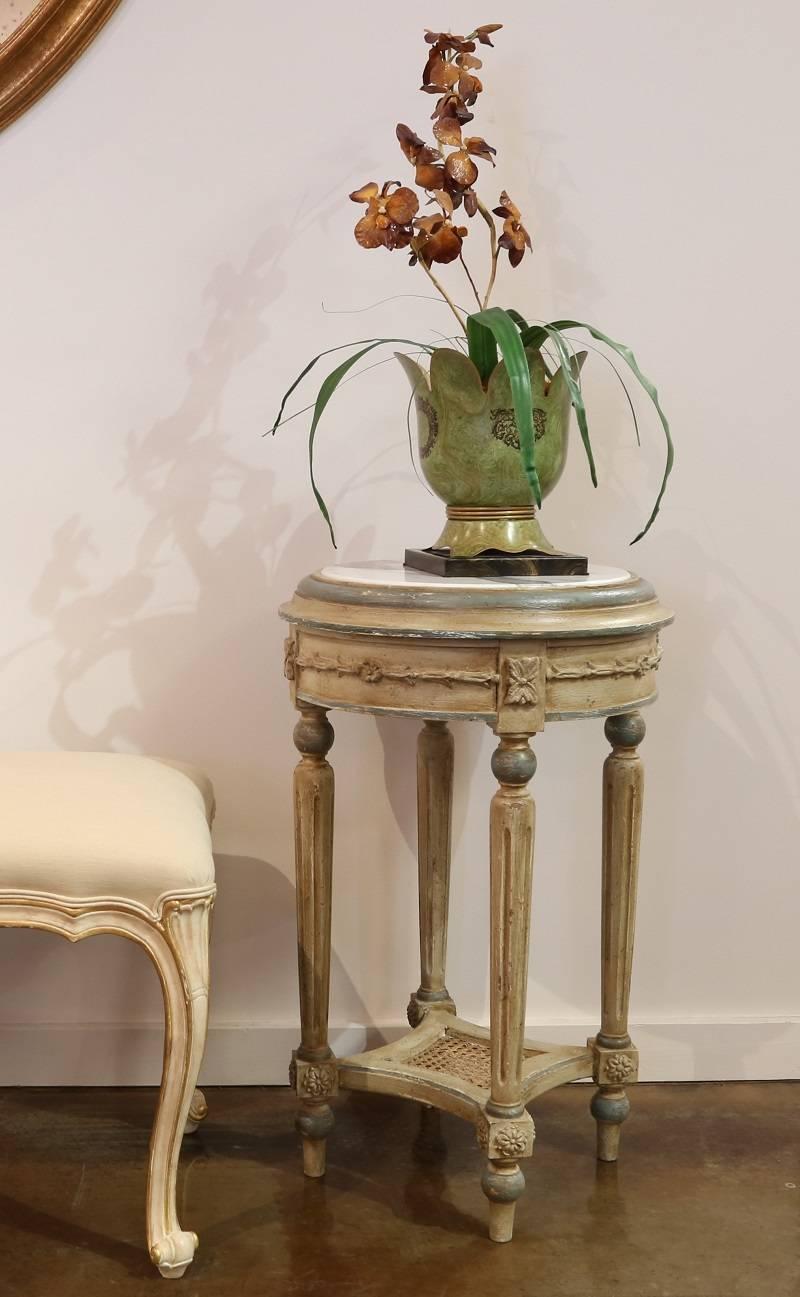 Hand-carved wooden side table with four legs and a woven stretcher in shades of ivory accented with blue, featuring a shaped, marble top. Created in Italy.