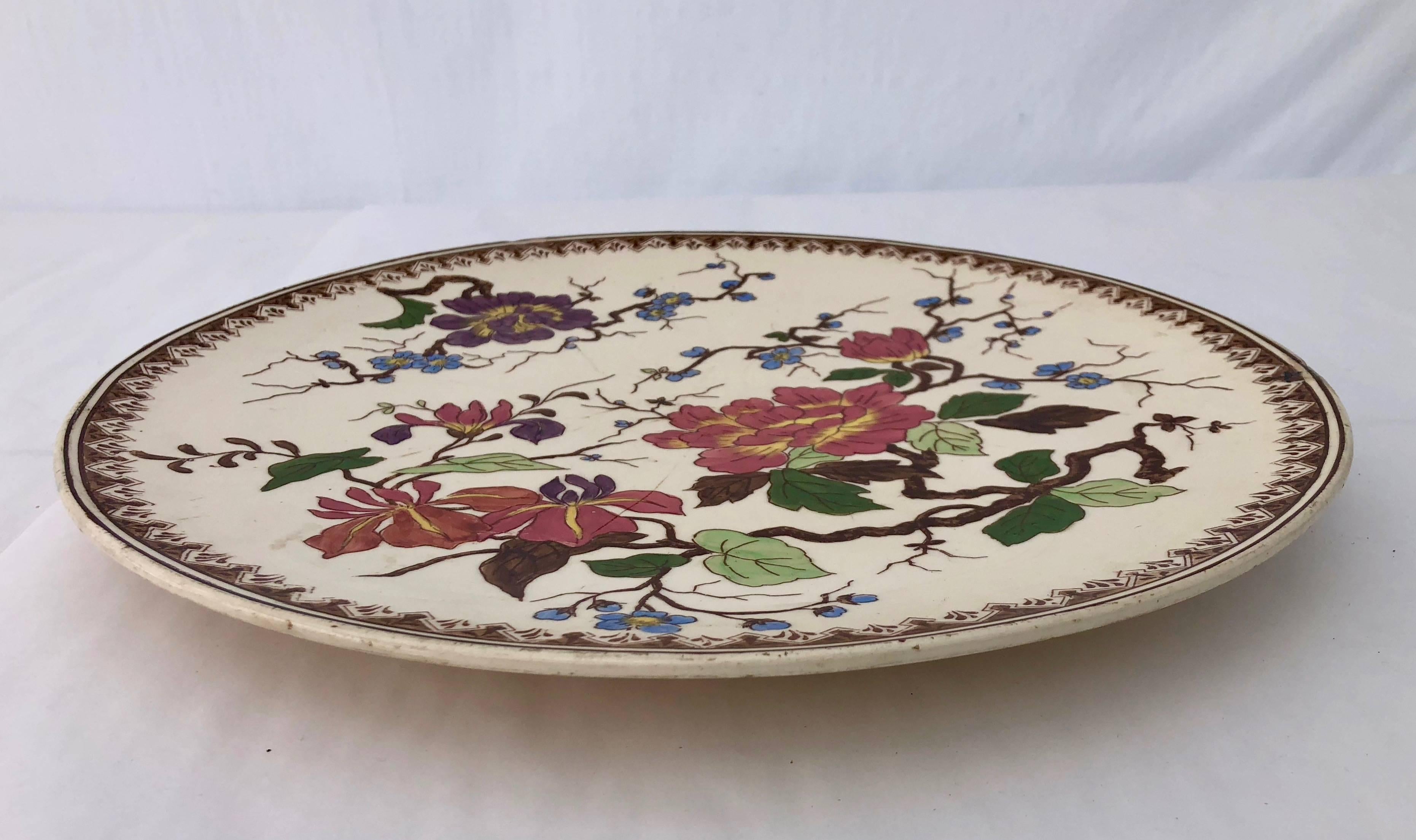 This is a beautiful round porcelain Imari platter with a hand painted floral design. The colors are vibrant pink, greens, brown, purple and blue. It has a small pedestal which gives the platter a built in lift for better presentation.