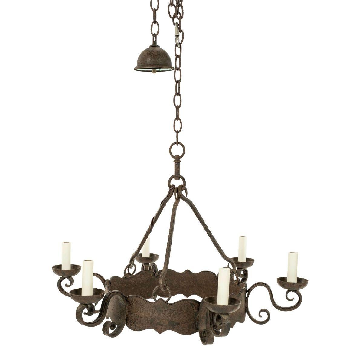 Round heavy iron chandelier dating to the late 19th or early 20th century. Decorative round scalloped band iron chandelier with six scrolled arms. Newly wired for use within the USA using UL listed parts. Includes chain and canopy. Height measured