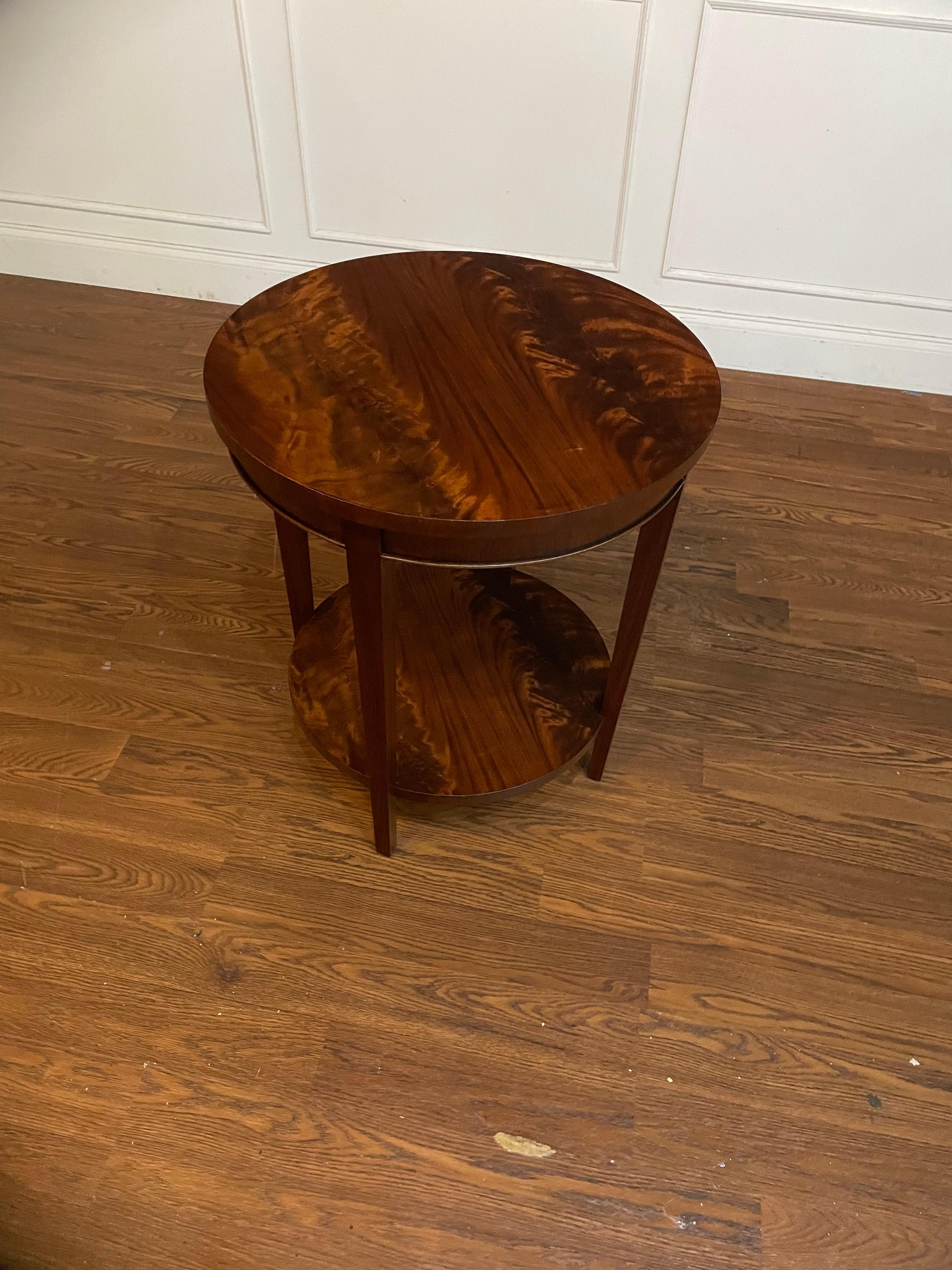This is a round Hepplewhite style mahogany side table made to order in our shop in Suwanee, Georgia.  It features classic Hepplewhite styling with square tapered legs.  The top and the lower shelf have a reverse slip match pattern of swirly crotch
