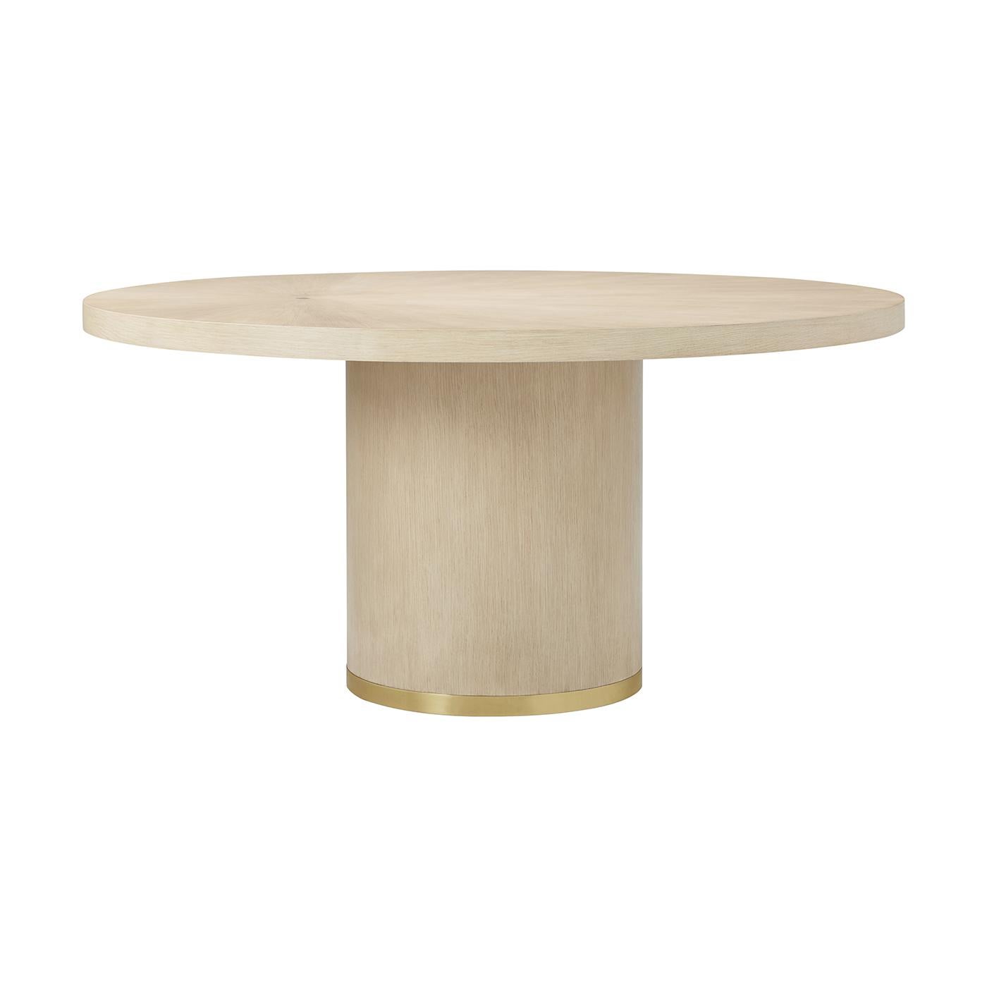 Meticulously designed and beautifully constructed, this round dining table features a light Martini finish that highlights its soft wood grain in a subtle radial pattern. The sleek circular top rests atop a bold cylindrical pedestal base, accented